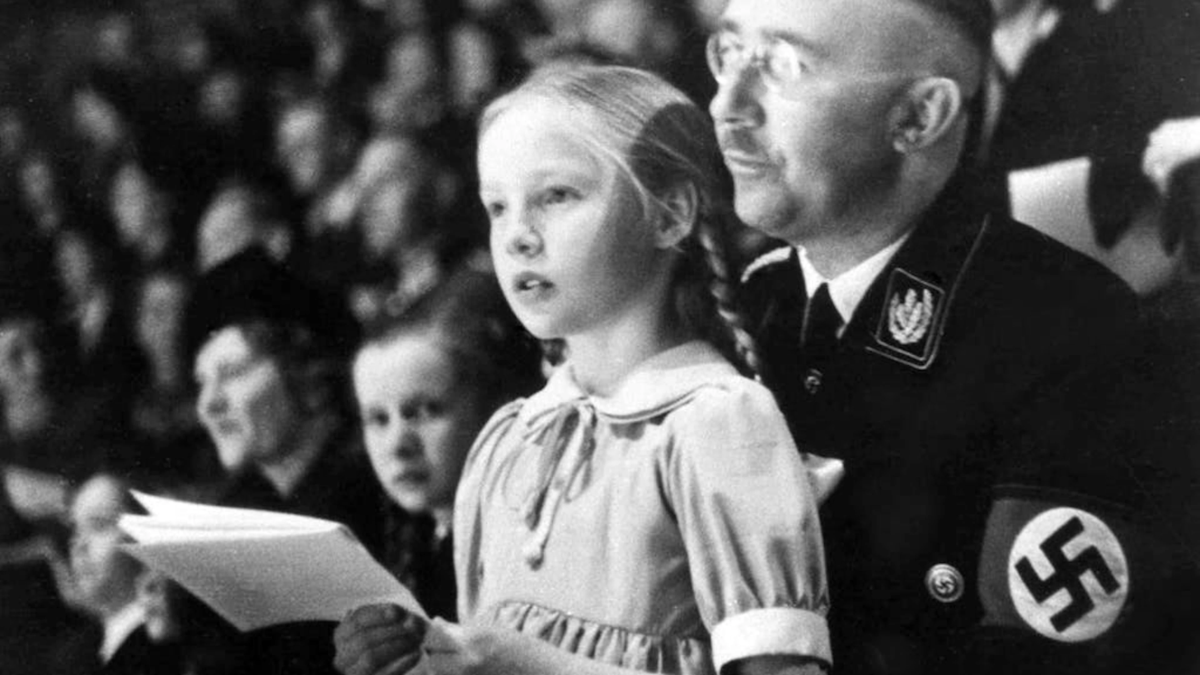 Gudrun Burwitz (1929-2018), l'unique fille biologique d'Heinrich Himmler, est restée active au sein de groupements d'extrême droite jusqu'à un âge avancé. Elle n'a jamais pris ses distances par rapport à son père et à ses crimes. Sur la photo, on peut voir le Reichsführer-SS avec sa fille Gudrun lors d'une manifestation sportive organisée à Berlin en mars 1938.