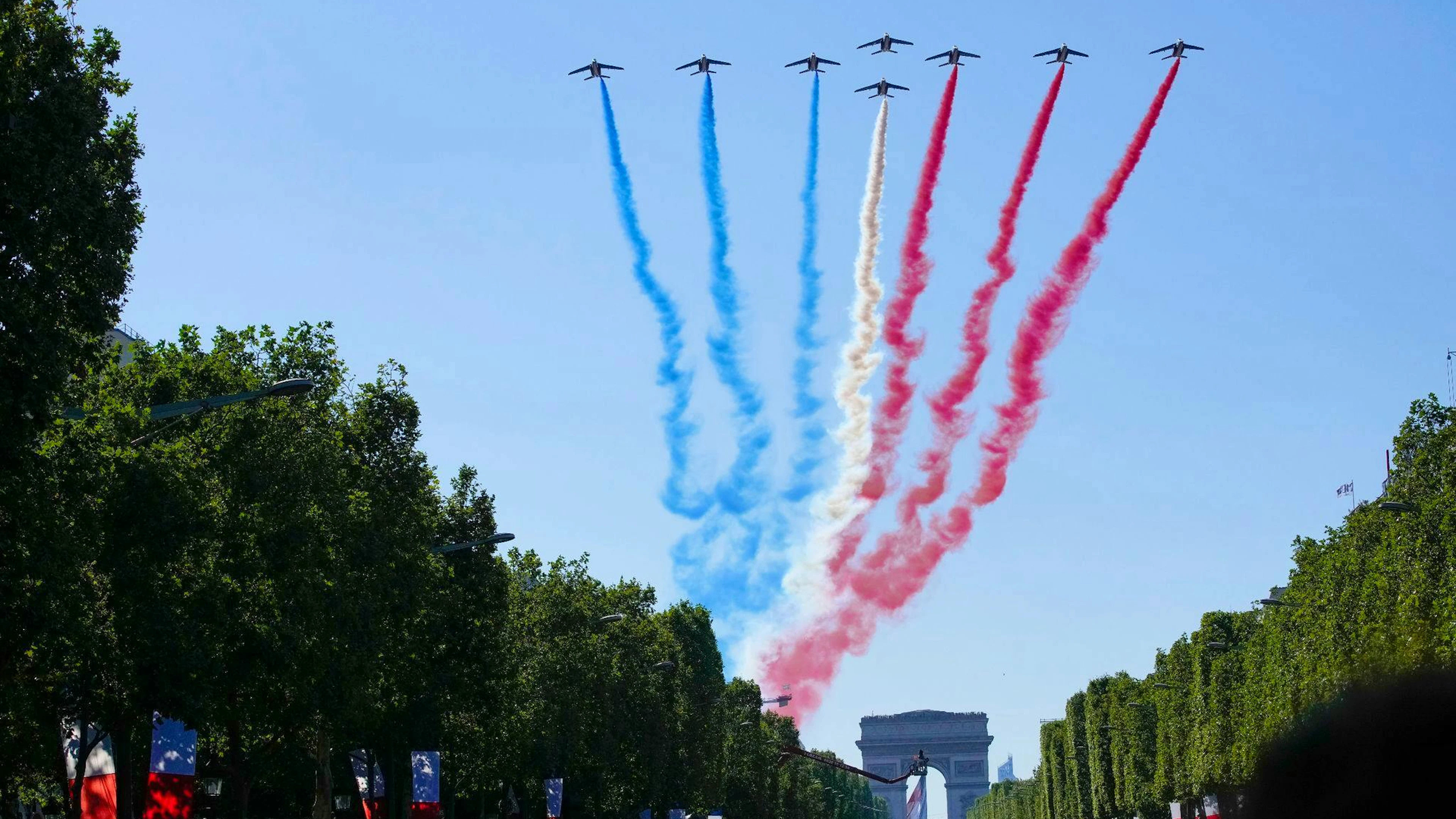 Jets der Patrouille de France fliegen über den Arc de Triumph und die Champs Elysees.