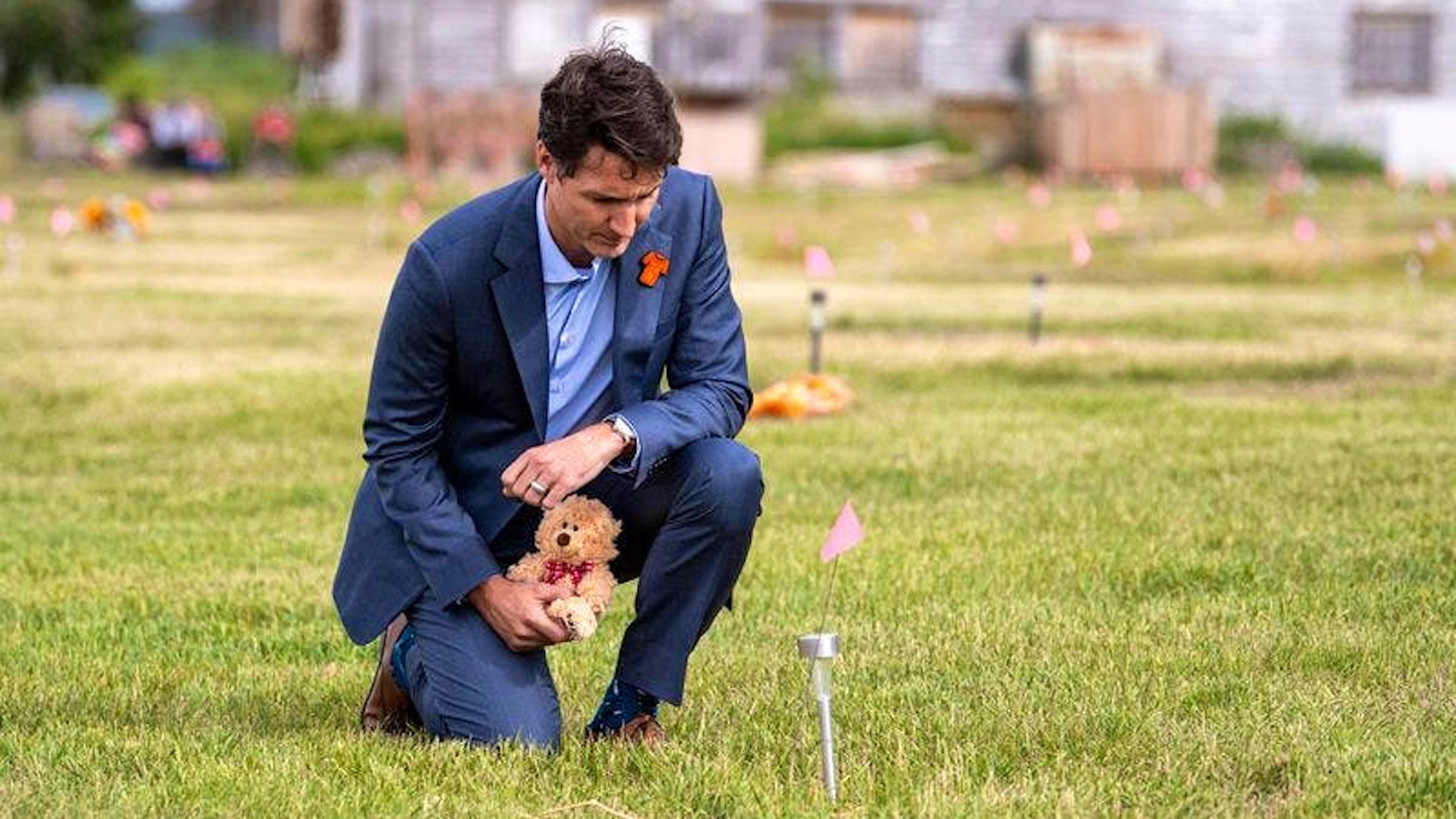 Justin Trudeau, Premierminister von Kanada, legt am 6. Juli 2021 einen Teddybär neben einer kleinen, in den Boden gesteckten Flagge auf dem Gelände einer ehemaligen Internatsschule in Cowessess nieder. Im Vormonat wurden  hiermit Hilfe eines Bodenradars 751 unmarkierte Gräber entdeckt. (Archiv9