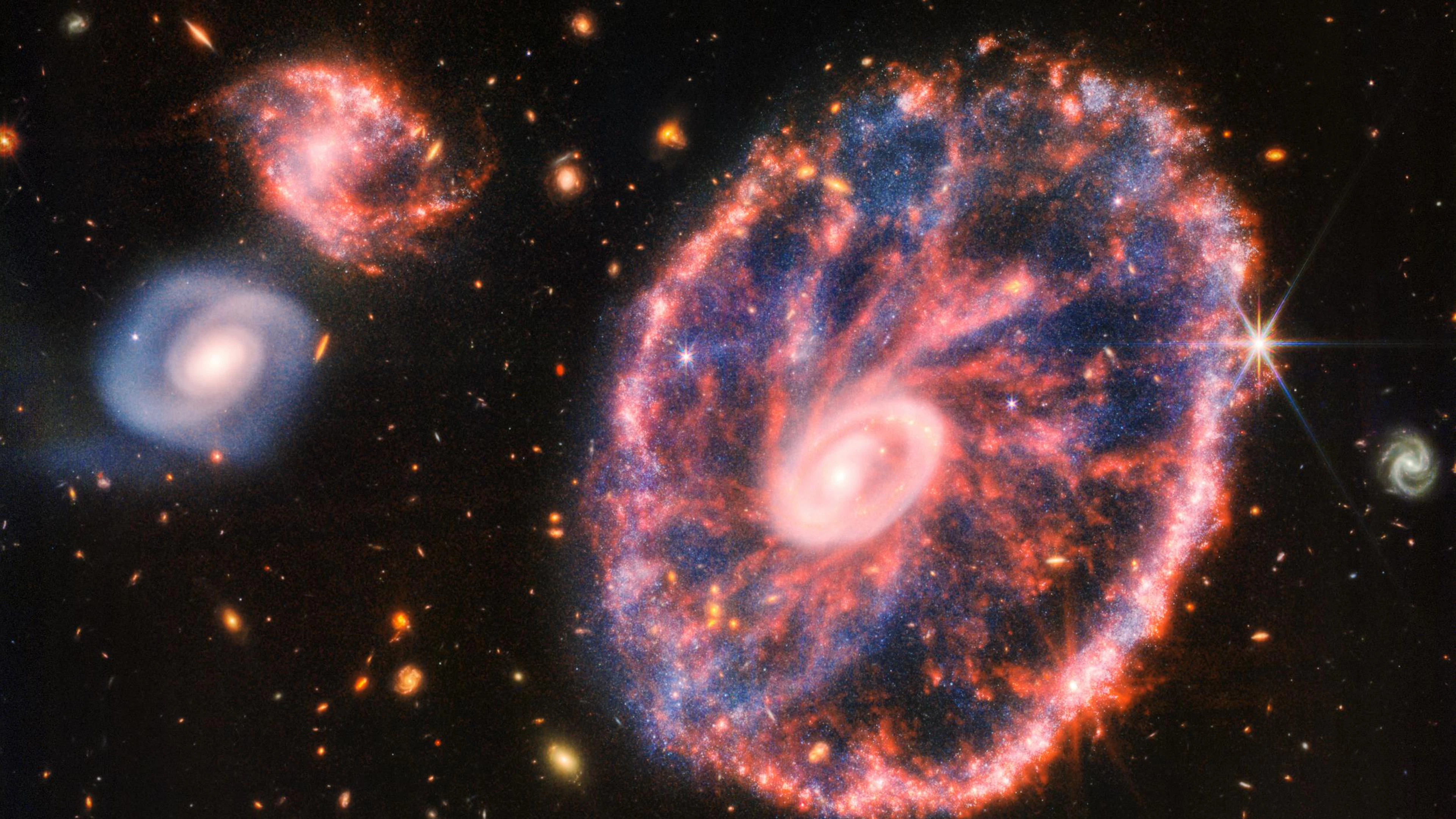 Das ist die «Cartwheel Galaxy», also Wagenrad-Galaxis. Vor und 400 Millionen Jahren sind hier Galaxien zusammengestossen. Im hellen, inneren Ring scheint die Spiralgalaxie erhalten geblieben zu sein. Rot glühender Staub aus Kohlenwasserstoff bildet davon ausgehend Streifen.