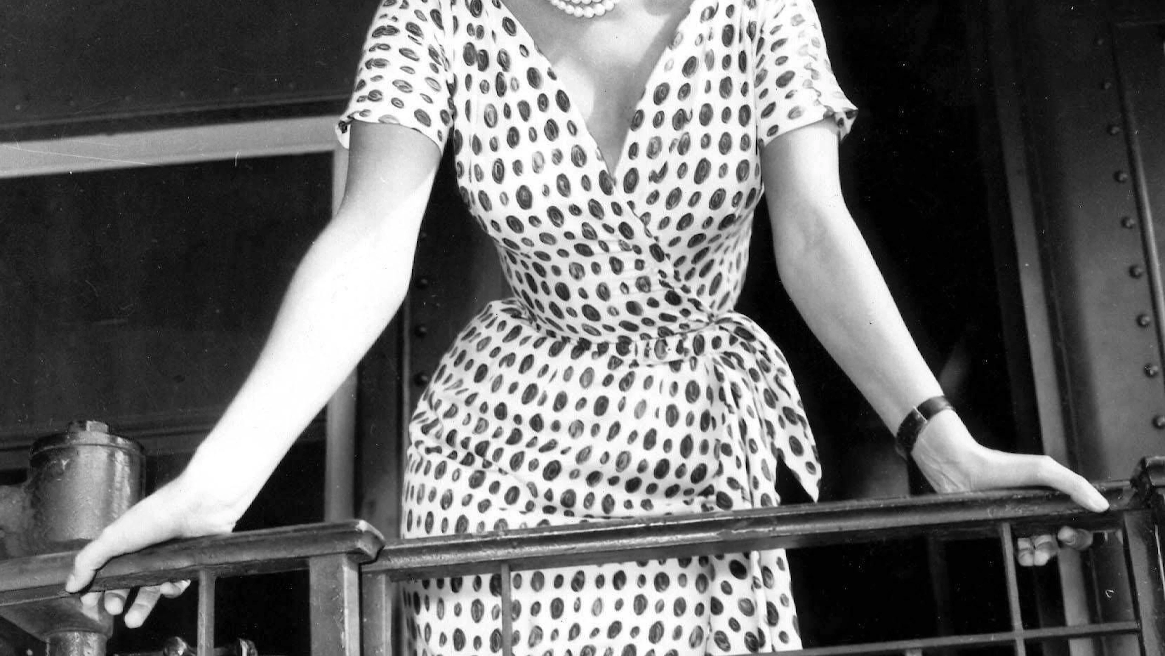 Am Bahnsteig eines Zuges: In der Garderobe der Schauspielerin taucht das Polka-Dots-Muster immer wieder auf. Hier auf einem knielangen Wickelkleid, das sie mit einem Hut mit breiter Krempe kombiniert.