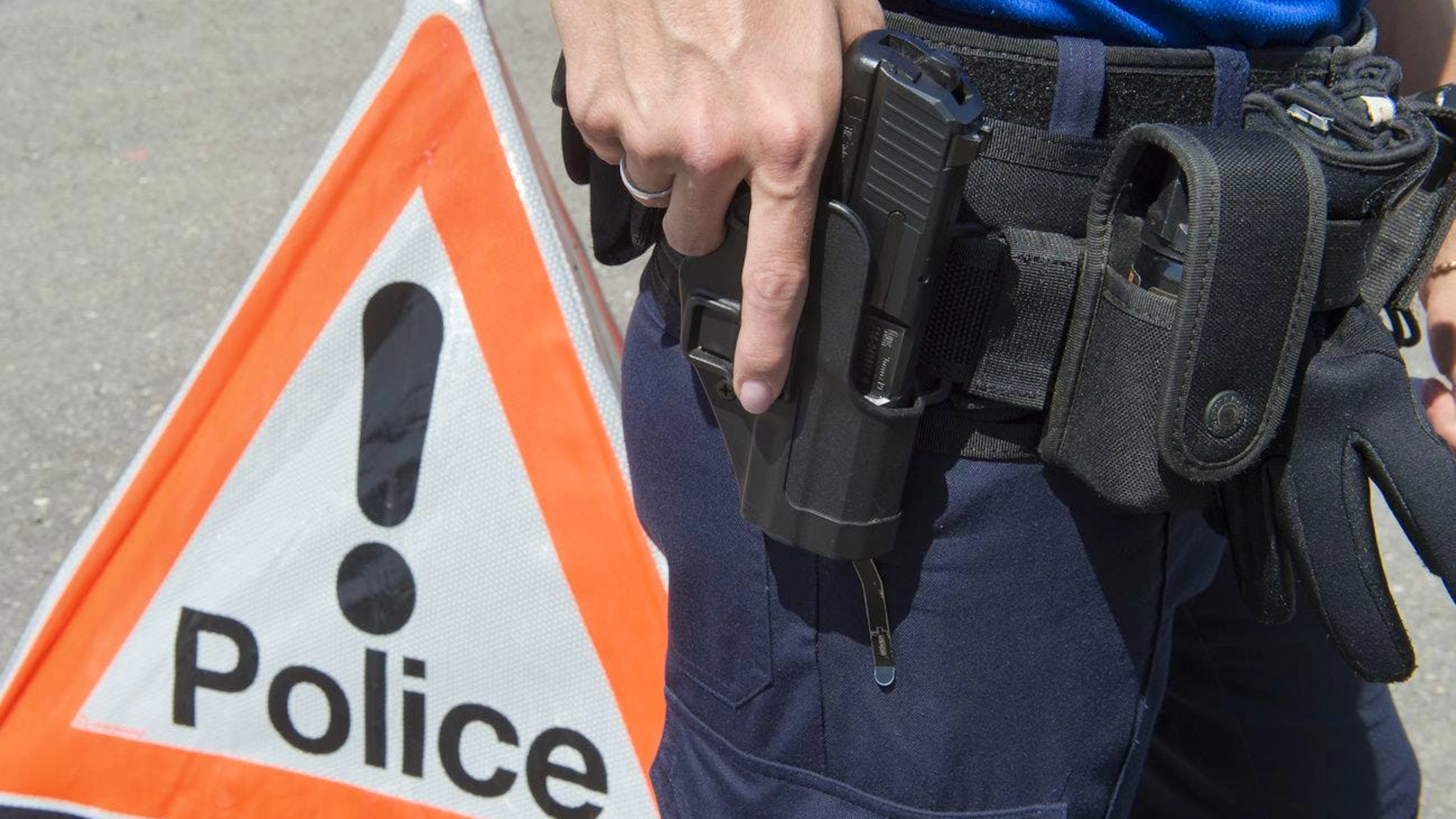 Un policier de la Police cantonale neuchateloise tient son pistolet devant un signe police, le 5 juin 2015, a Neuchatel. (KEYSTONE/Sandro Campardo) 

Ein Polizist der Kantonspolizei Neuenburg greift nach seiner Pistole, am 5. Juni 2015, in Neuenburg. (KEYSTONE/Sandro Campardo)