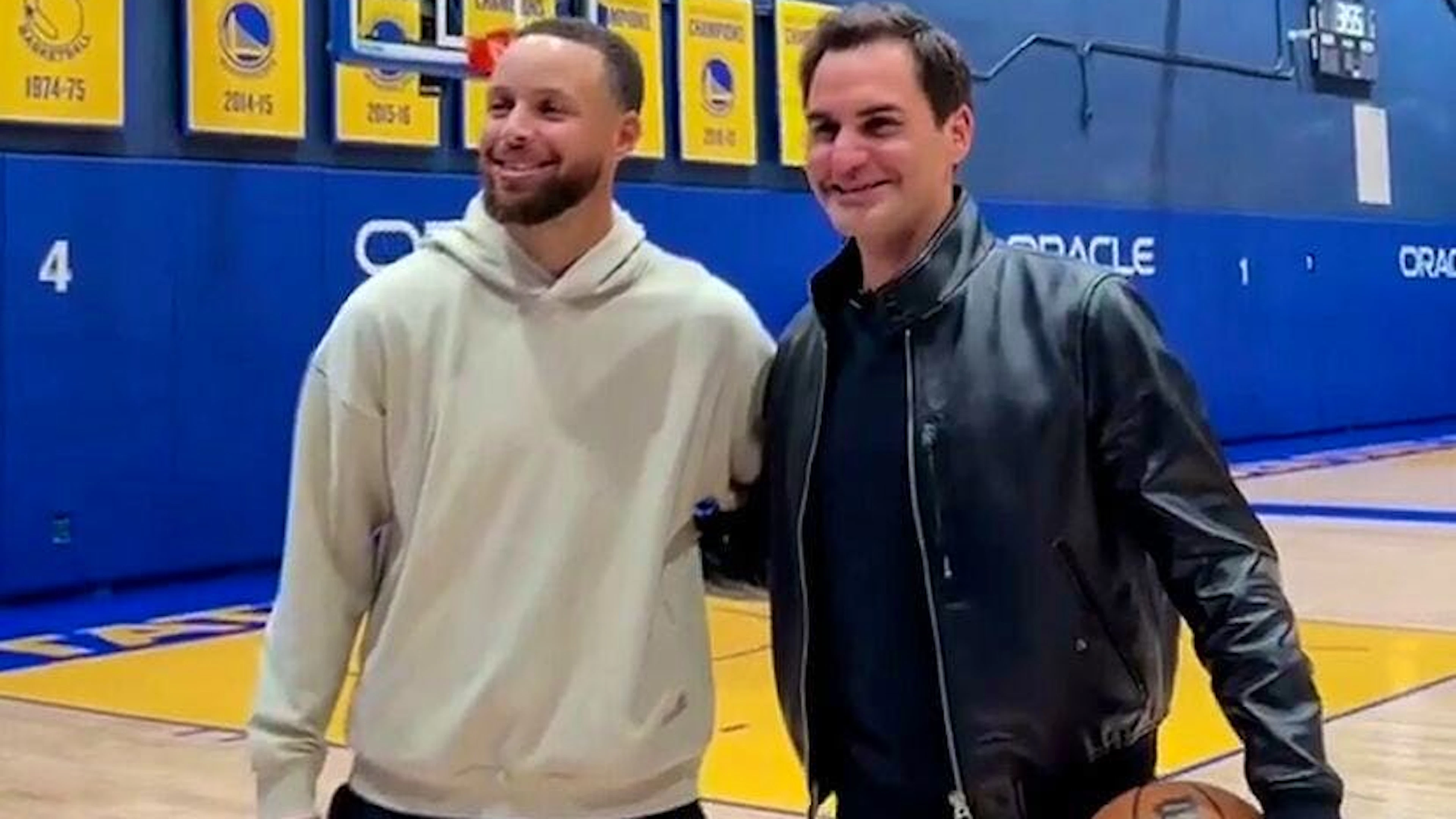 Stephen Curry und Roger Federer strahlen im Chase Center in die Kameras.