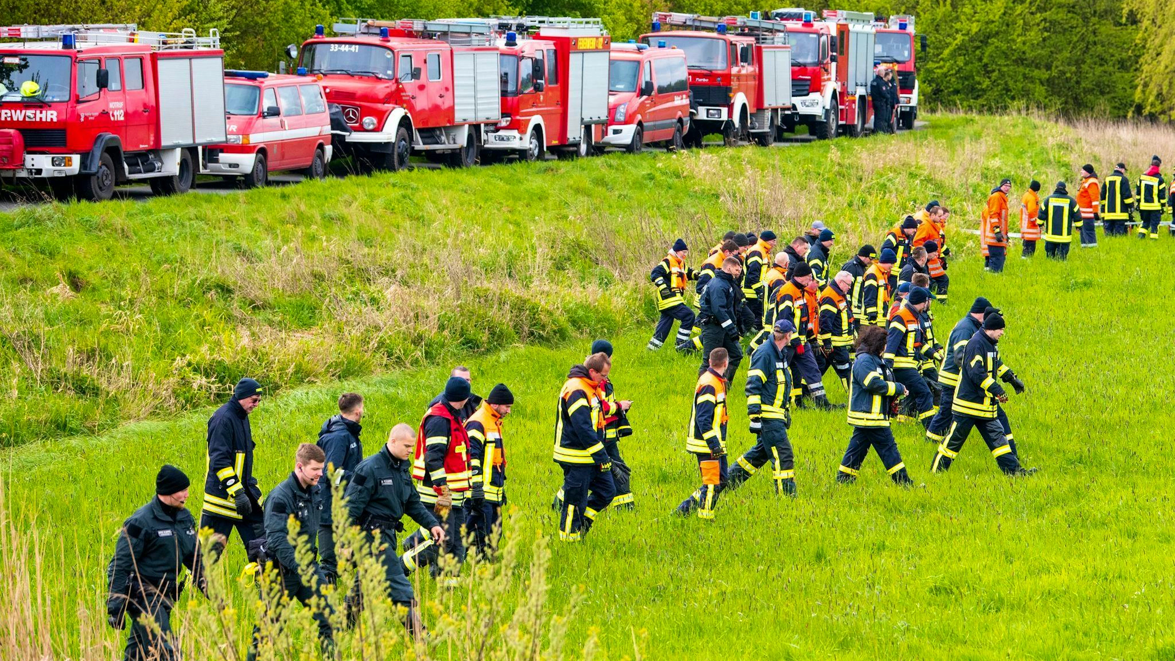 Feuerwehrleute und Polizisten suchen auf einem Feld nach dem vermissten Arian.