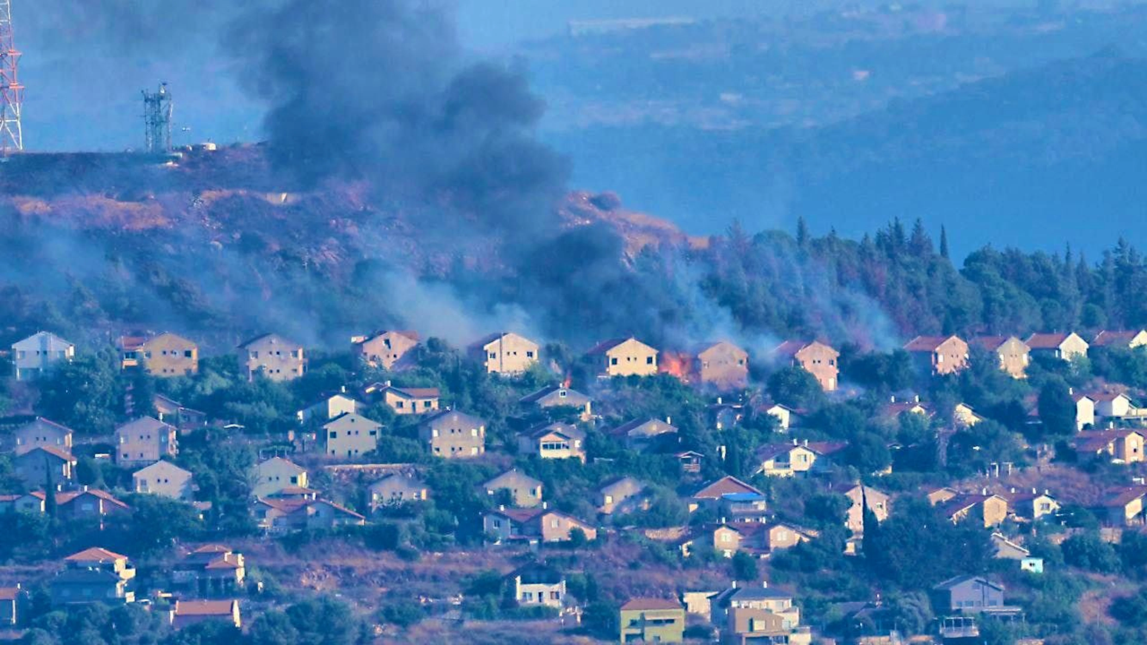 ARCHIVE - Fire and black smoke rise between houses in the northern Israeli border town of Metula, which was shelled by Hezbollah, photographed from Marjayoun in southern Lebanon. Photo: Hussein Malla/AP/dpa