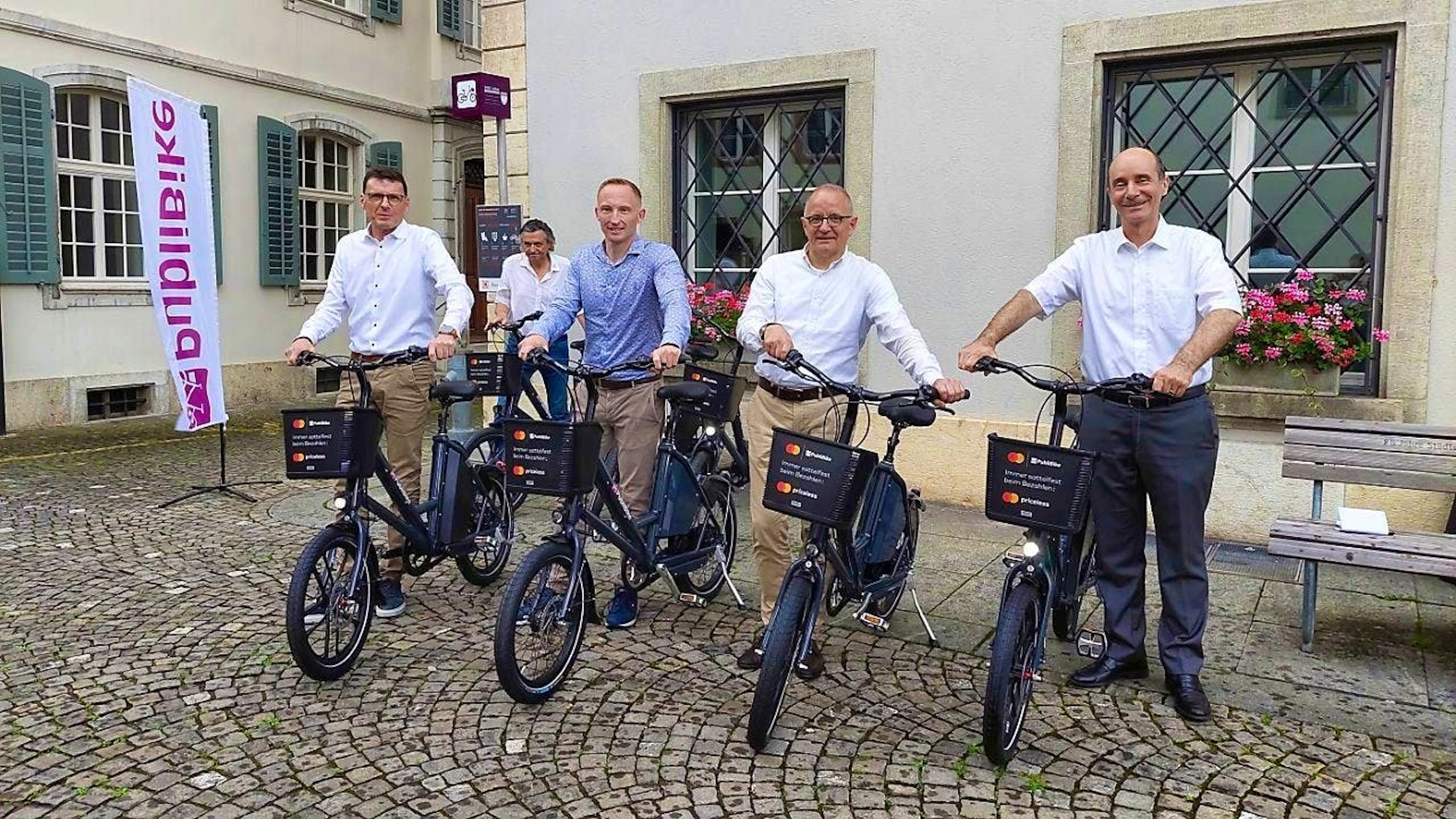 Deputy Mayor Werner Schib (right) and Mayor Hanspeter Hilfiker (second from right) open the new bike-sharing system at Aarau Town Hall.