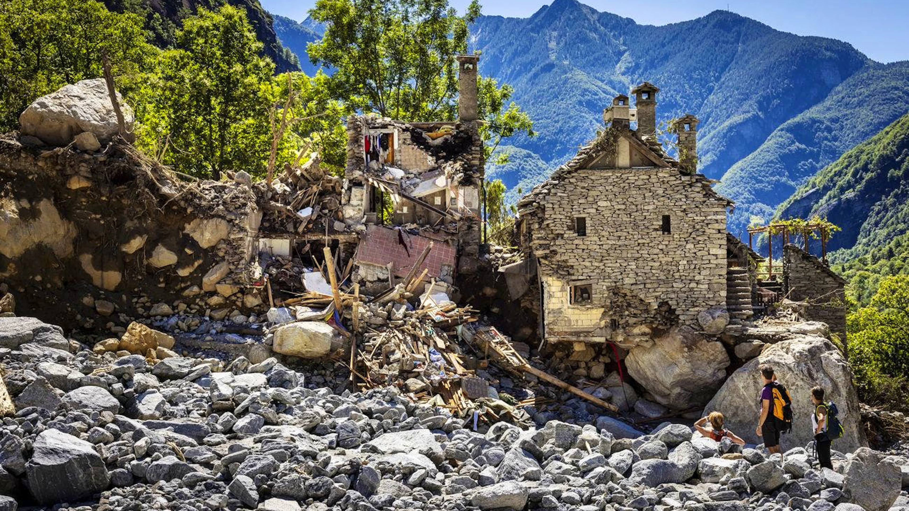 Alcune persone ispezionano le case distrutte nella massiccia frana causata dal maltempo a Fontana, in Val Bavona nella Vallemaggia.
