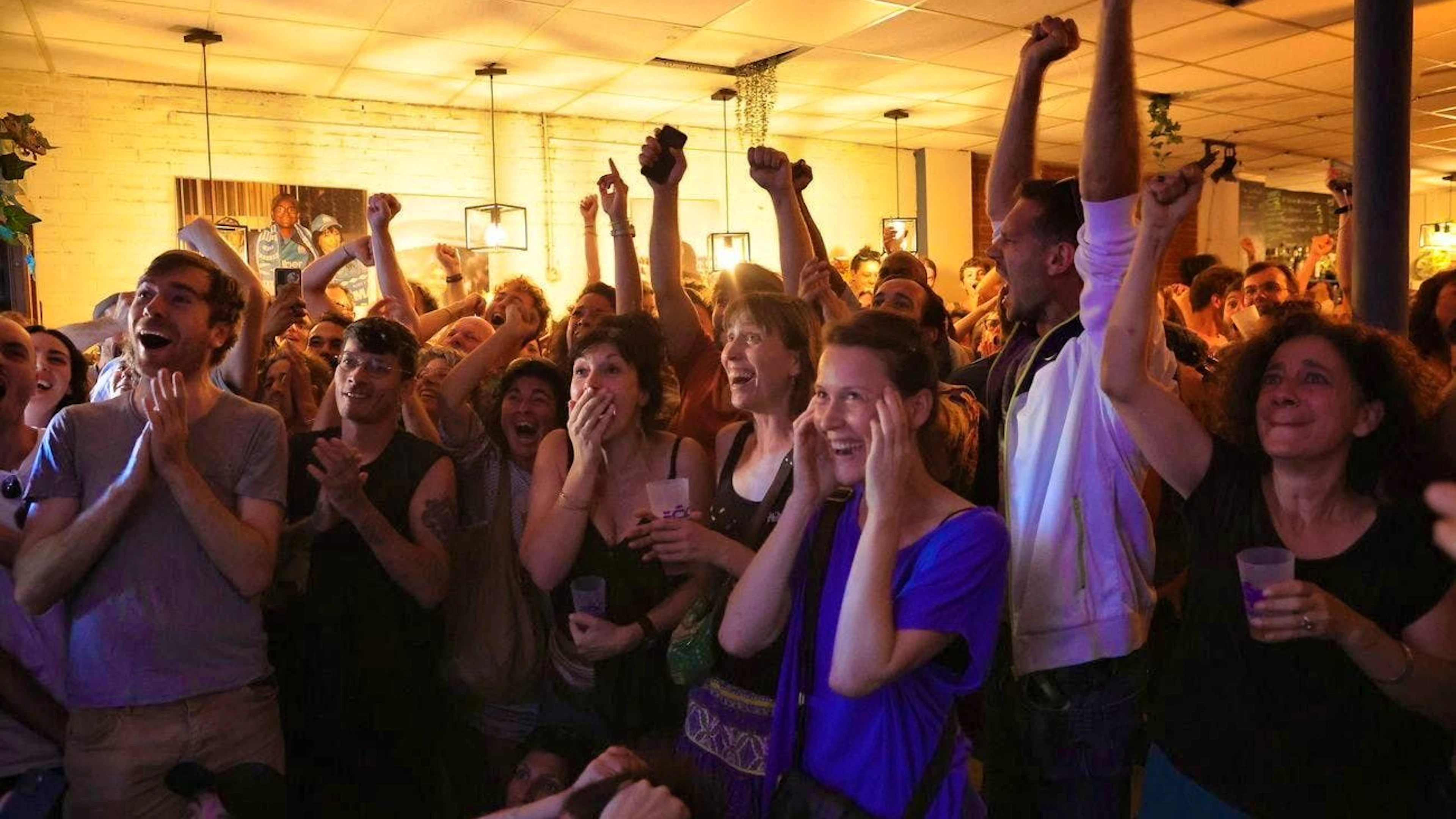 People react to the announcement of the election victory of Le Nouveau Front Populaire, a coalition of French left-wing parties, in a bar in the center of Marseille.