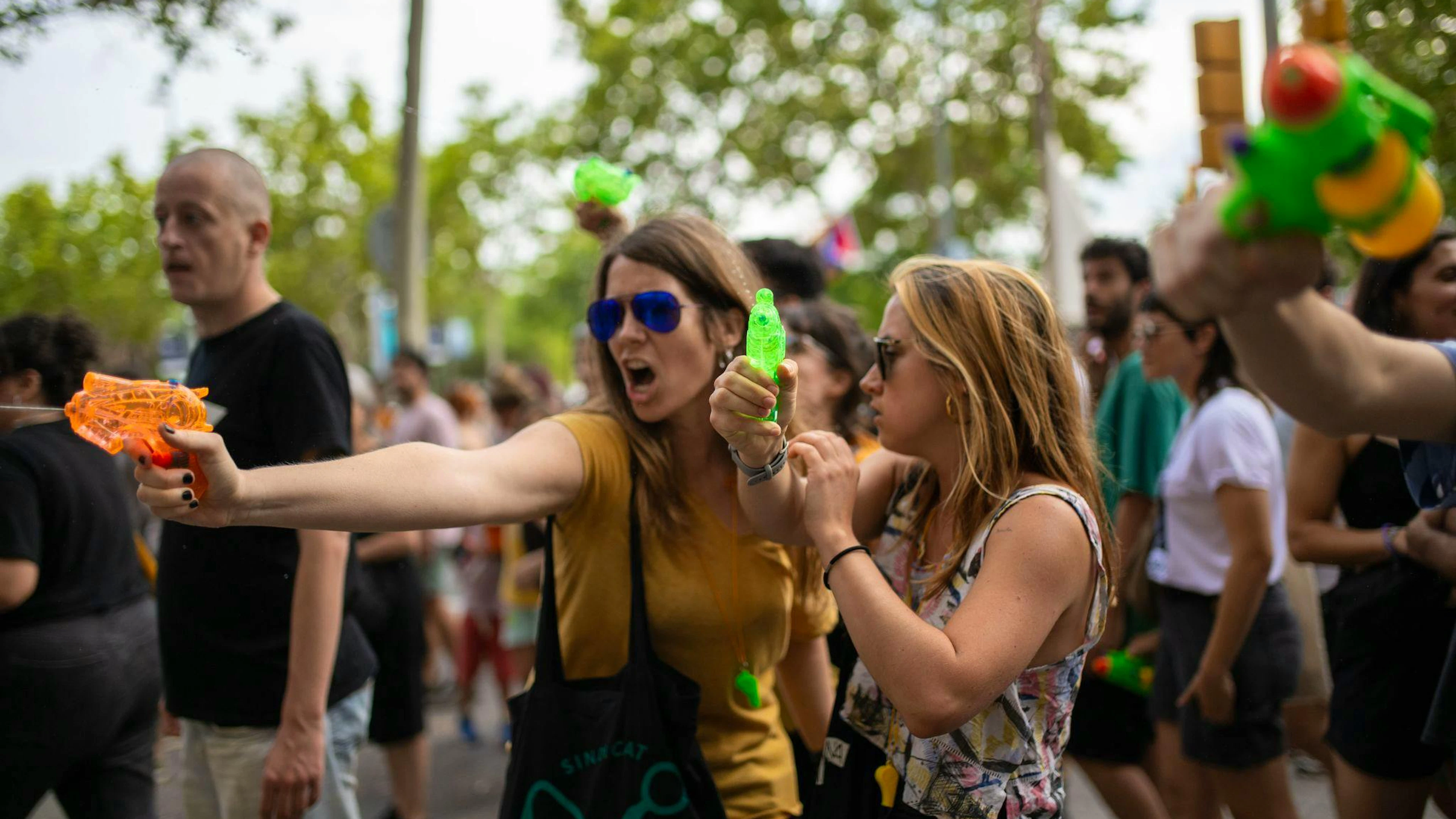 Demonstrantinnen verpassen Urlaubern eine unerbetene Abkühlung aus Wasserpistolen.