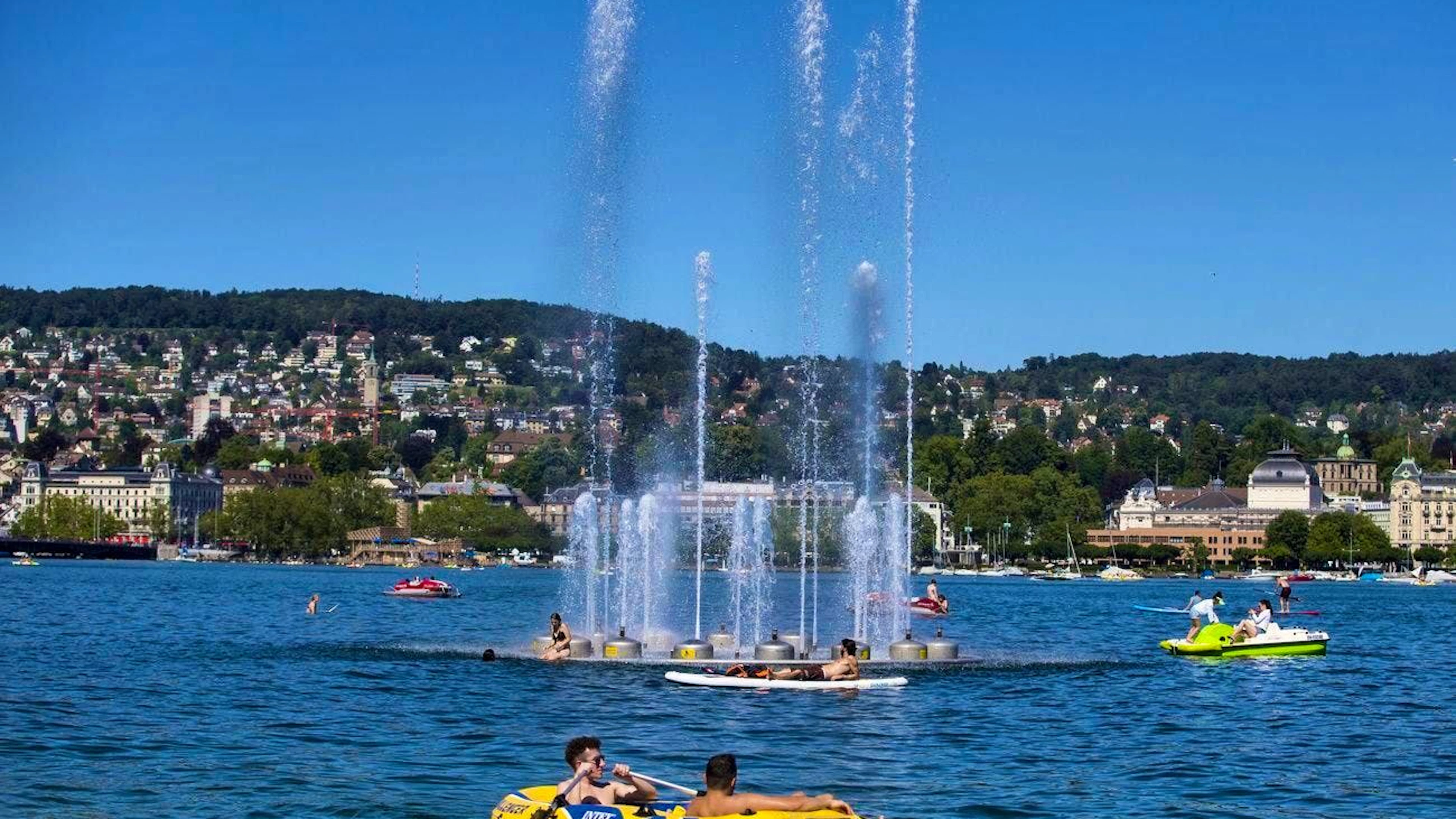 Des gens profitent du beau temps estival près de la fontaine du lac de Zurich, près du port d'Enge, mardi 19 juillet 2016, à Zurich. (KEYSTONE/Patrick B. Kraemer)