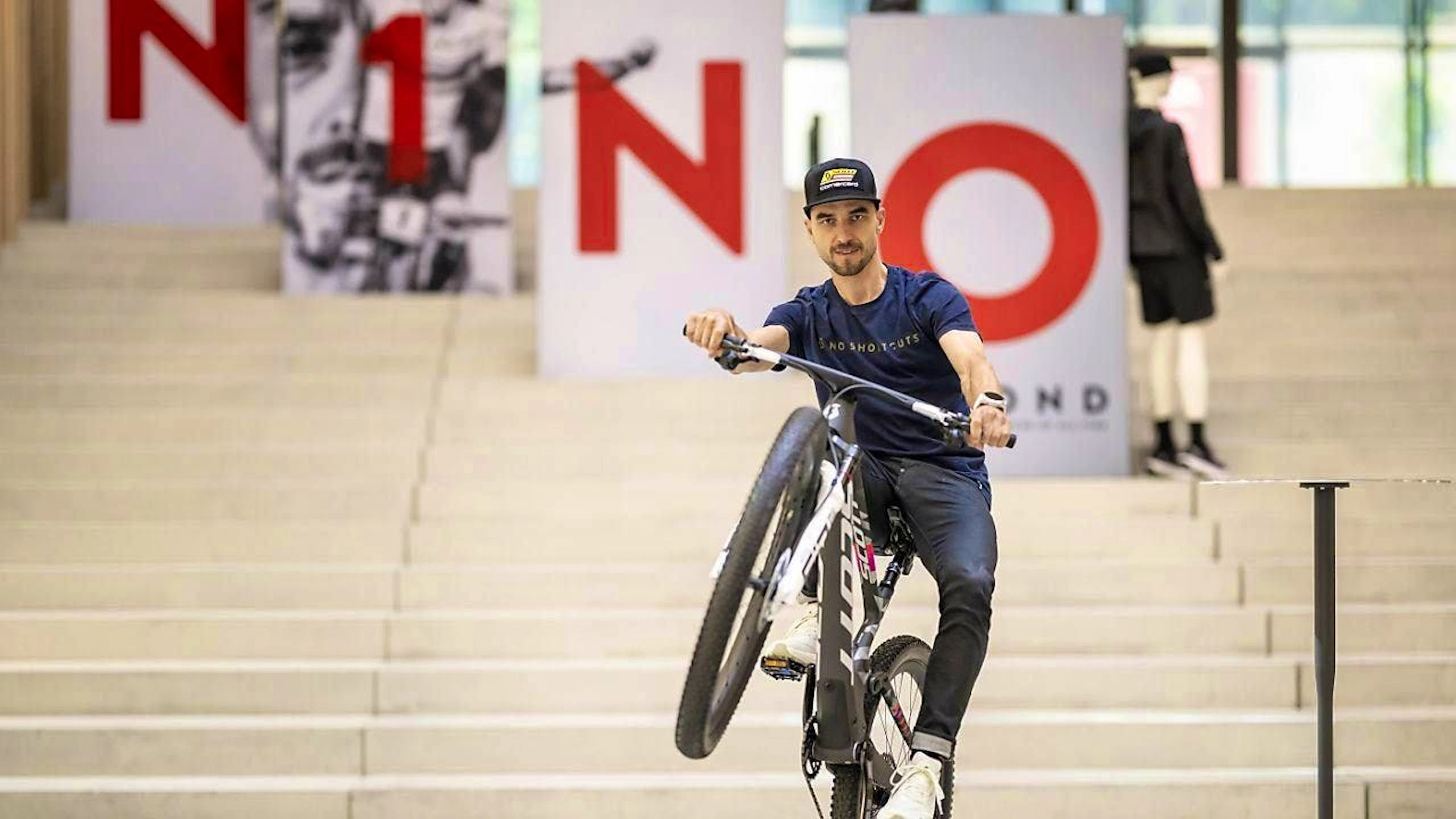 Nino Schurter does a wheelie on a replica of the bike he will be riding in Paris