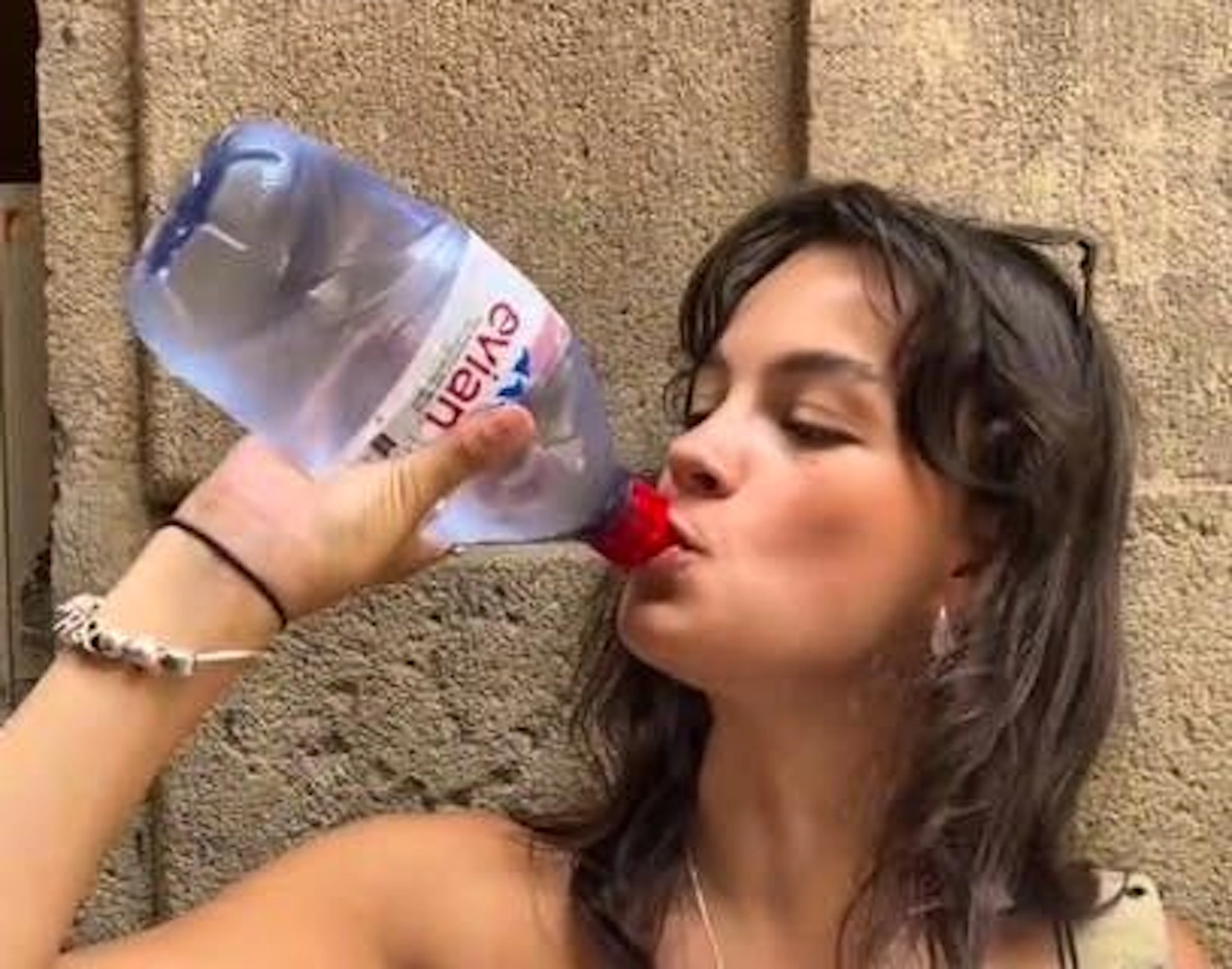 An American woman drinks demonstratively from a water bottle. 