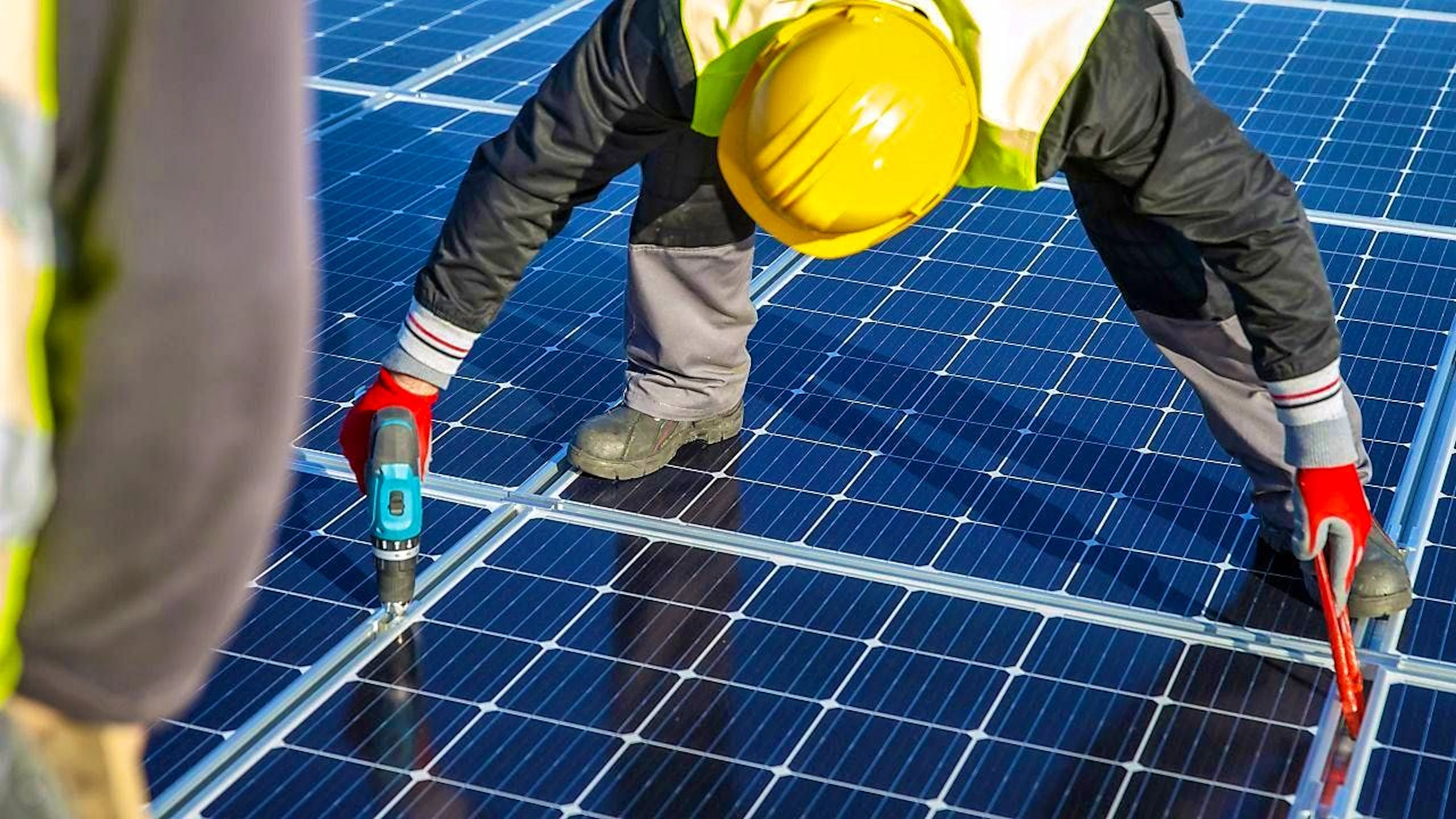 Workers installing solar panels on a roof. (symbolic image)