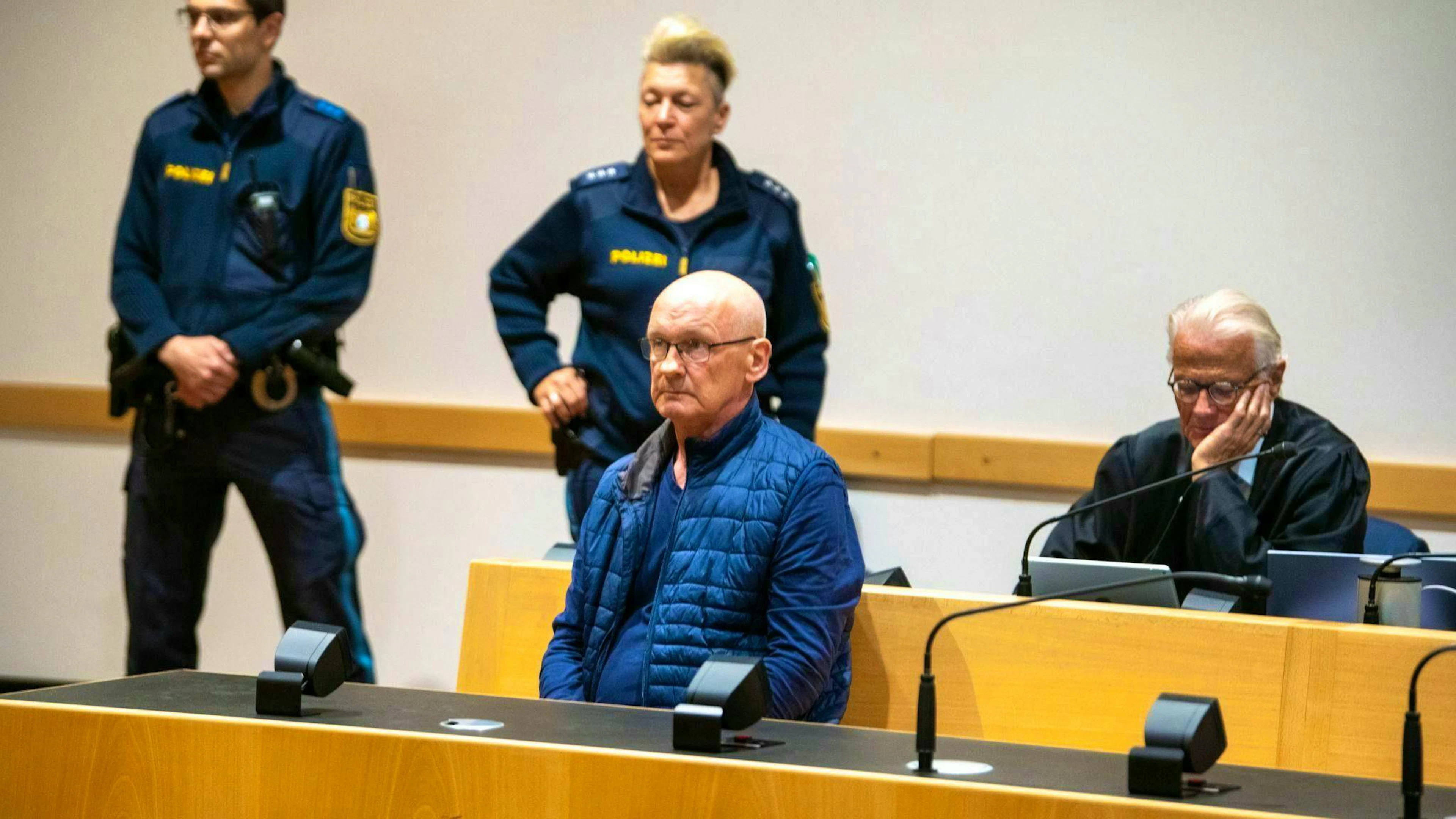 The man accused of murdering three neighbors is guarded by police officers in the courtroom. According to his lawyer, the man does not want to be made unrecognizable in pictures. (archive photo)