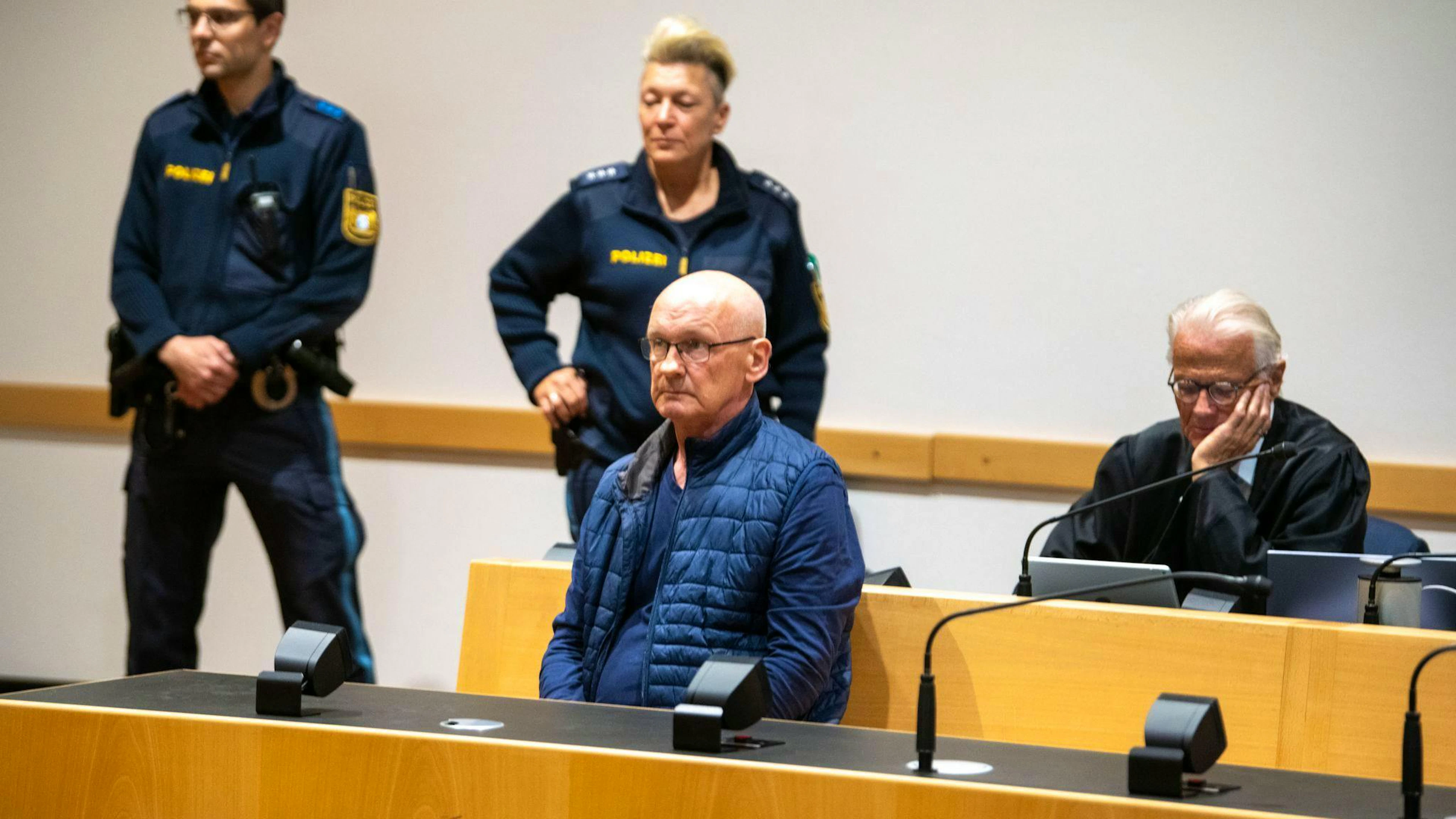 Der wegen der Ermordung von drei Nachbarn angeklagte Mann wird im Gerichtssaal von Polizisten bewacht. Der Mann will nach Angaben seines Anwalts auf Bildern nicht unkenntlich gemacht werden. (Archivfoto)