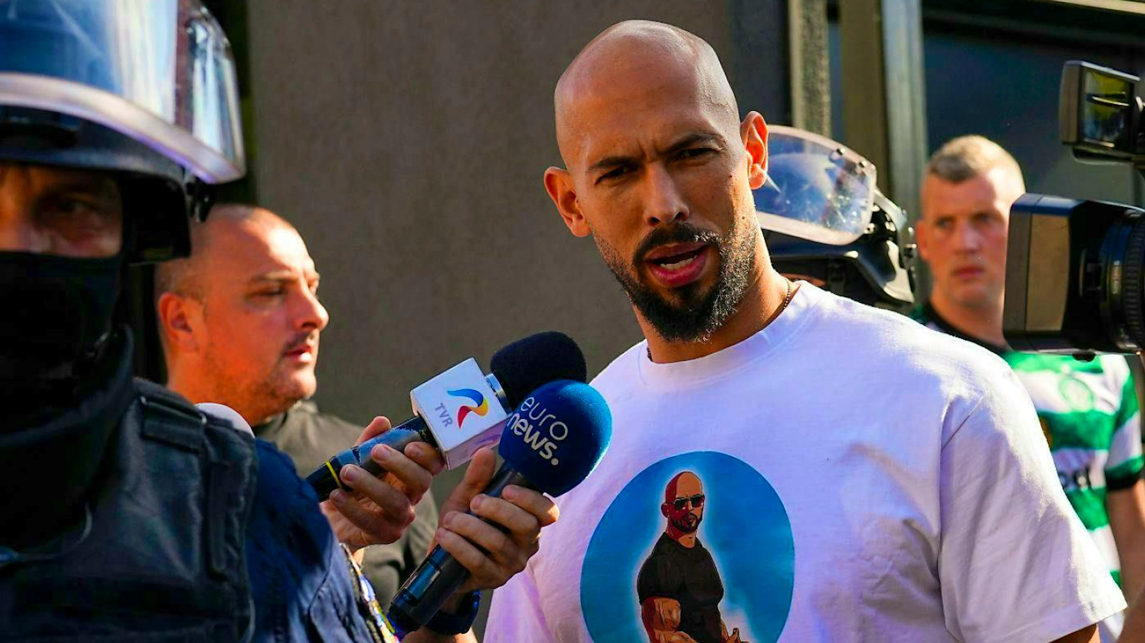 Andrew Tate speaks to the media as he is taken for questioning following a police raid on his home on the outskirts of Bucharest.