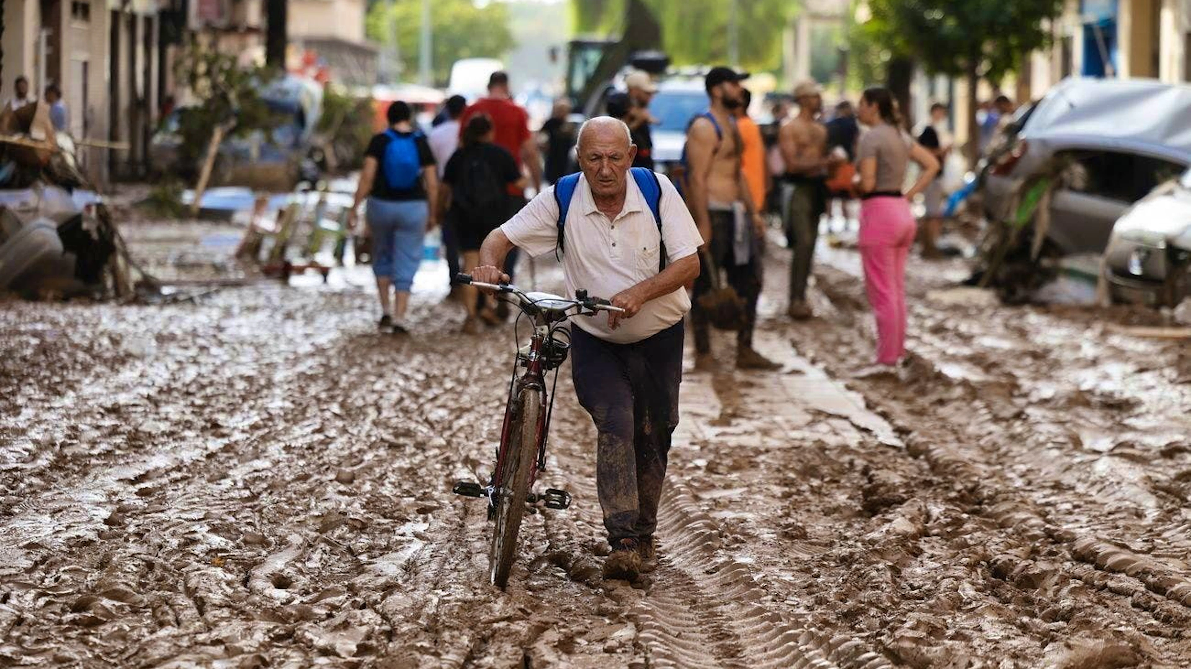 A man pushes his bicycle over the mud in Valencia