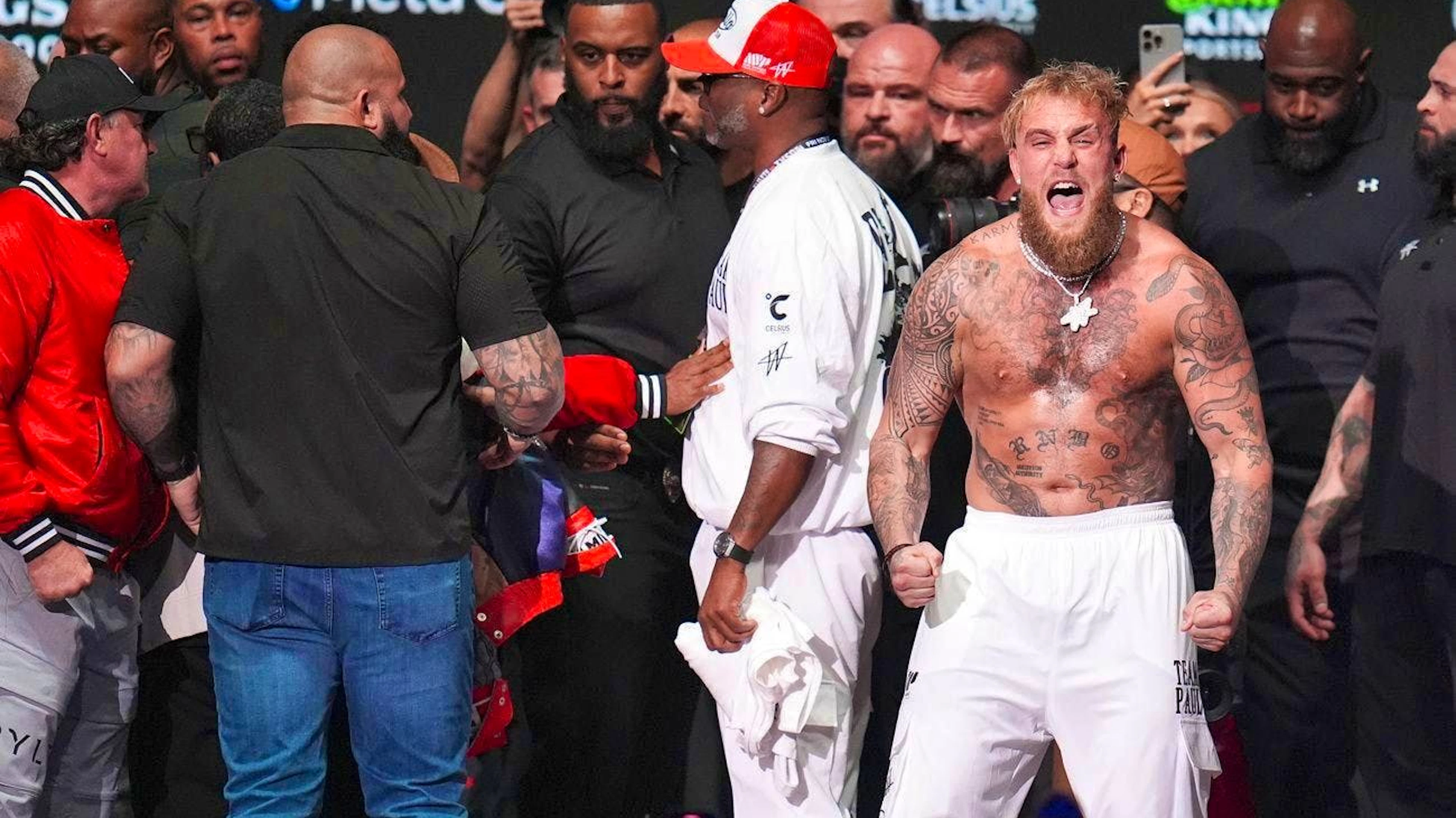 While Tyson is being held back, Paul (white trousers) shouts something in the direction of the photographers.