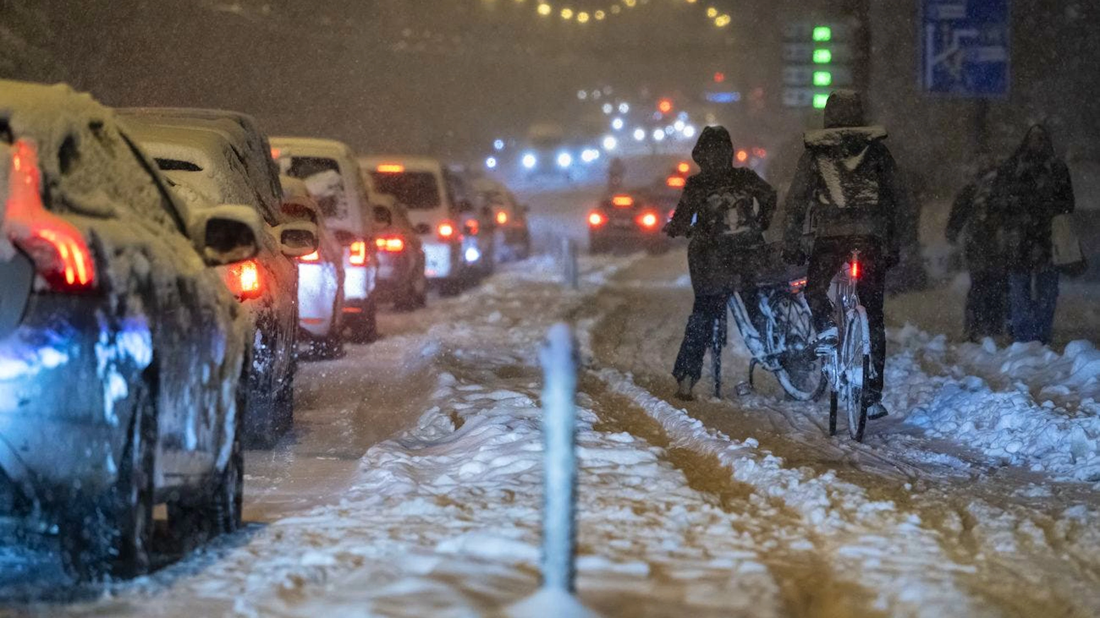 Des voitures sont bloquées par de fortes chutes de neige tandis que des cyclistes tentent de rester dans leur voie, jeudi 21 novembre 2024 sur le pont de la Lorraine à Berne. La tempête de neige a largement paralysé le trafic de soirée à Berne jusque dans les quartiers. (KEYSTONE/Alessandro della Valle)