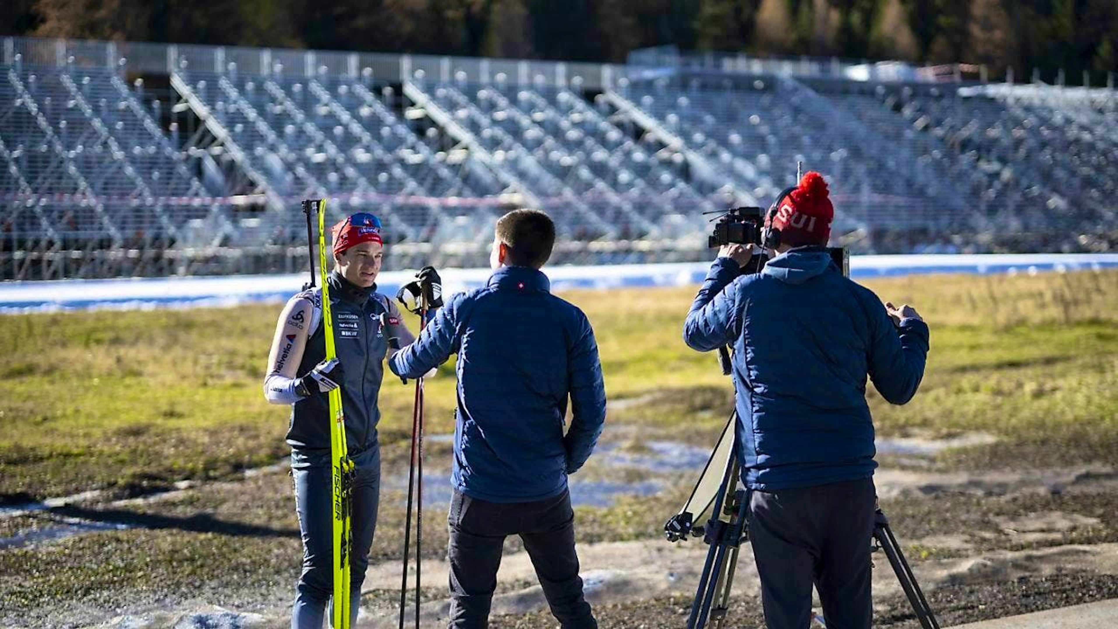 Niklas Hartweg gives information about the start of the season in Lenzerheide, while the buildings for the Biathlon World Championships are already being constructed in the background