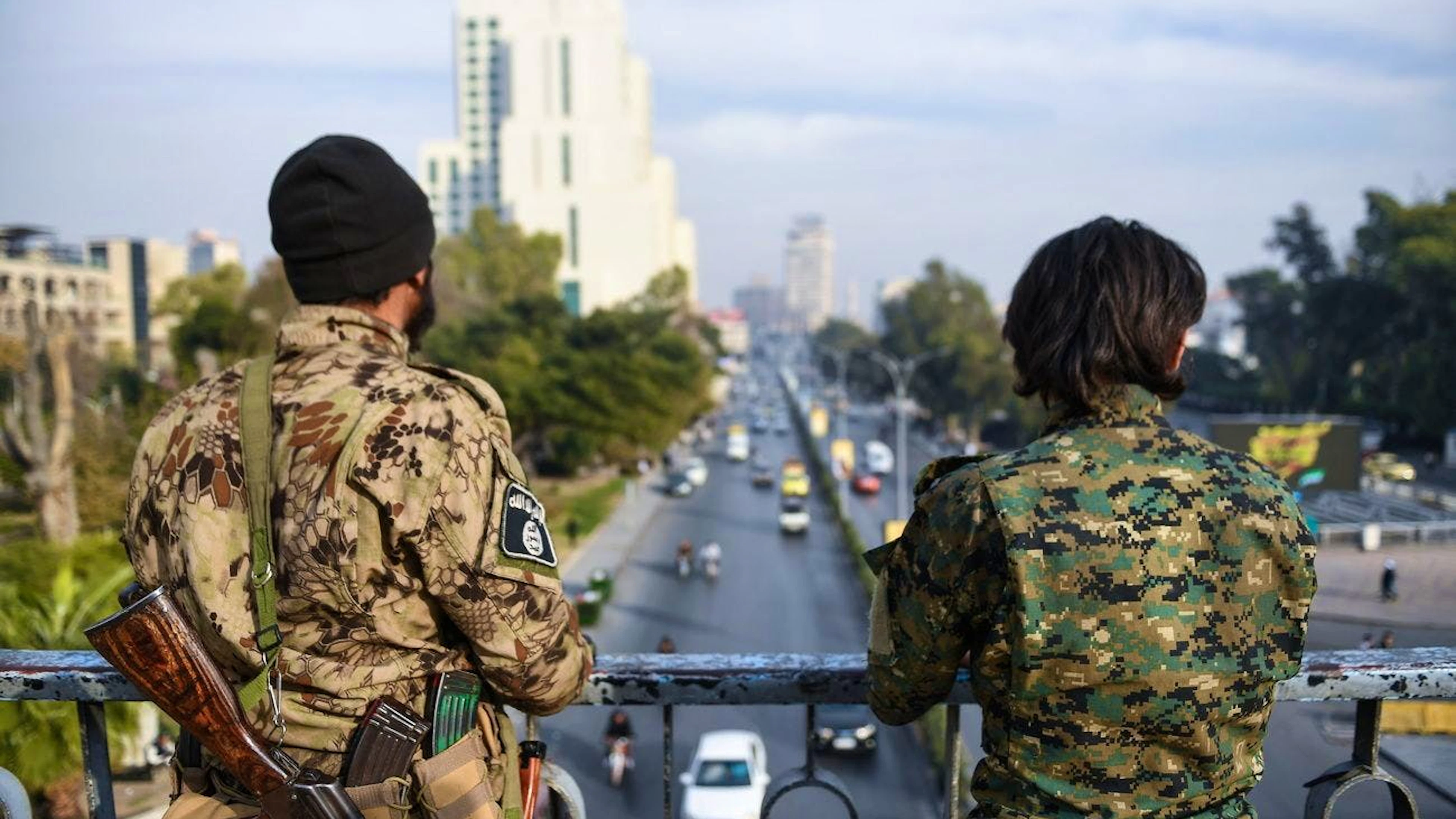 Due uomini armati sorvegliano una strada da un ponte a Damasco, Siria, 11 dicembre 2024. L'Amministrazione militare siriana ha annunciato l'11 dicembre la revoca del coprifuoco imposto a Damasco e ha esortato i residenti a tornare al loro posto di lavoro dopo la cacciata del presidente siriano al-Assad l'8 dicembre.