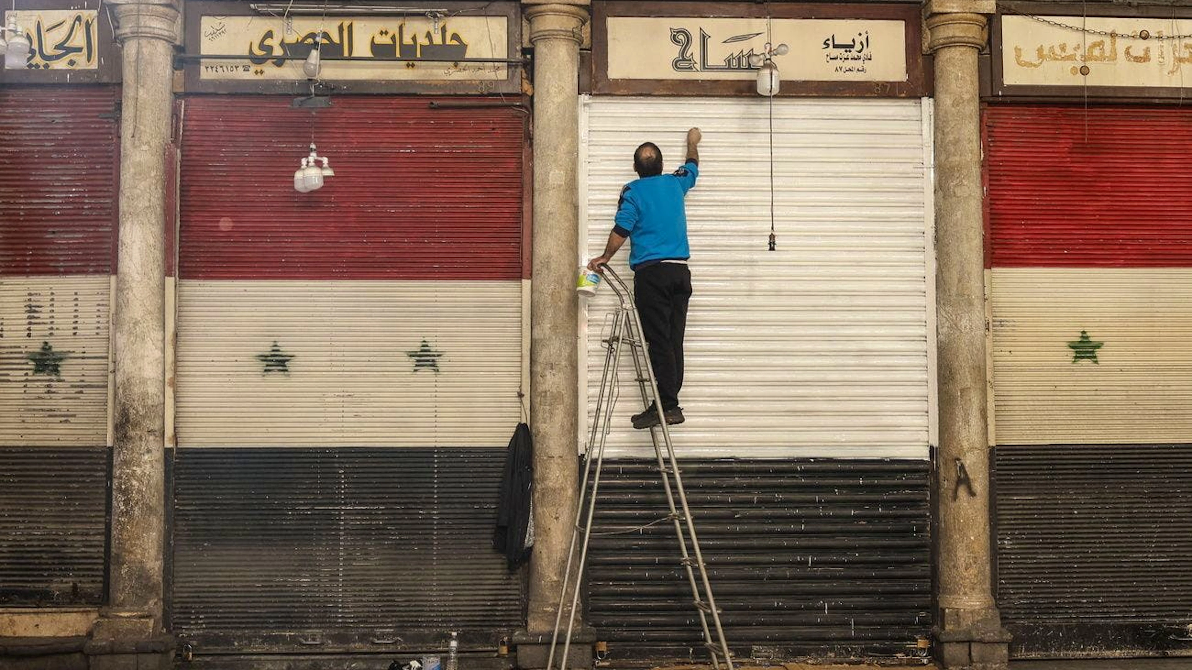 Un uomo dipinge la ringhiera del suo locale a Damasco, Siria, il 13 dicembre (immagine simbolica).
