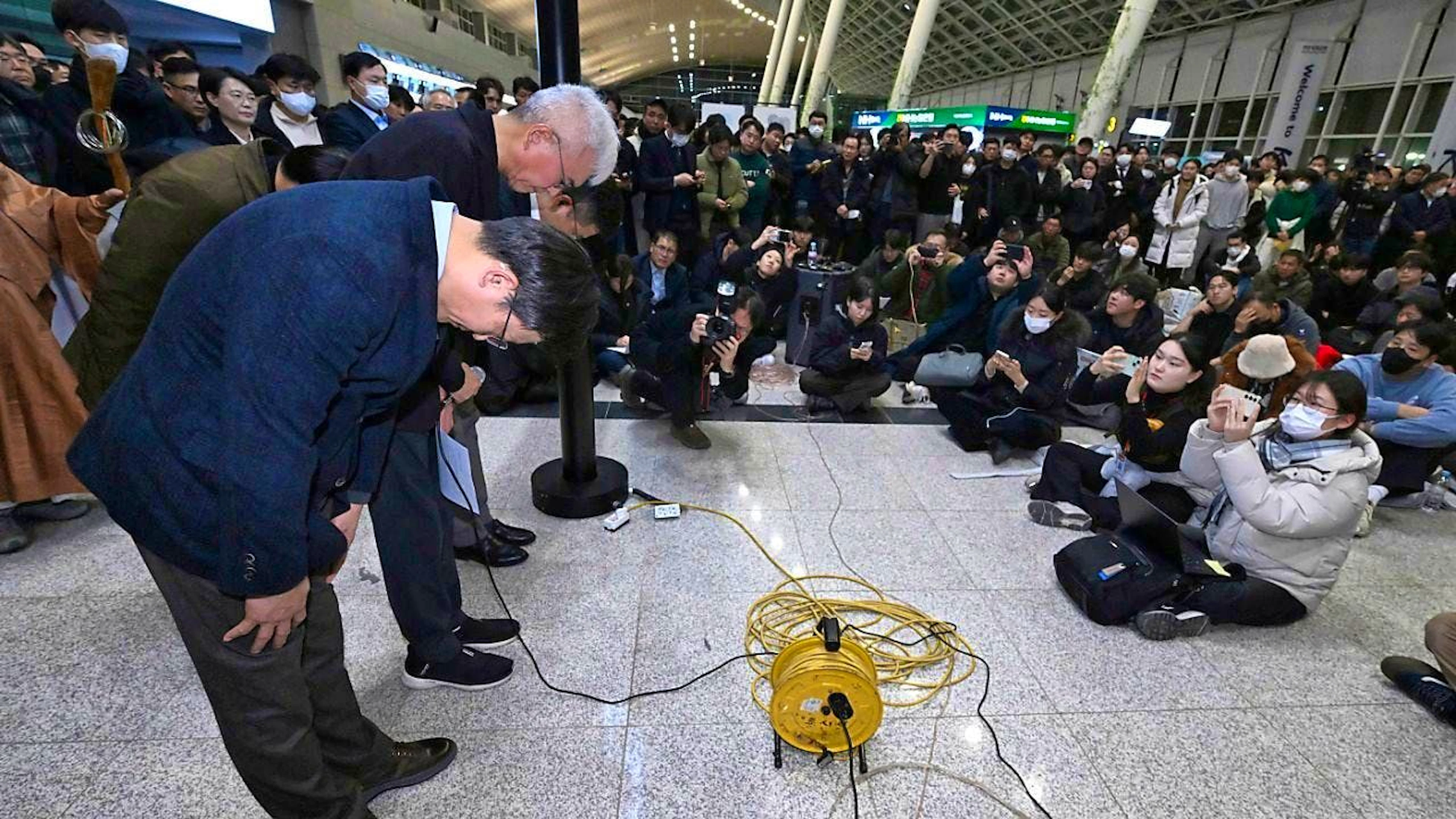 dpatopbilder - The CEO of Jeju Air, Kim E-bae (l), and other members of management bow to the relatives of the passengers at Muan International Airport. Photo: Uncredited/YONHAP/AP/dpa