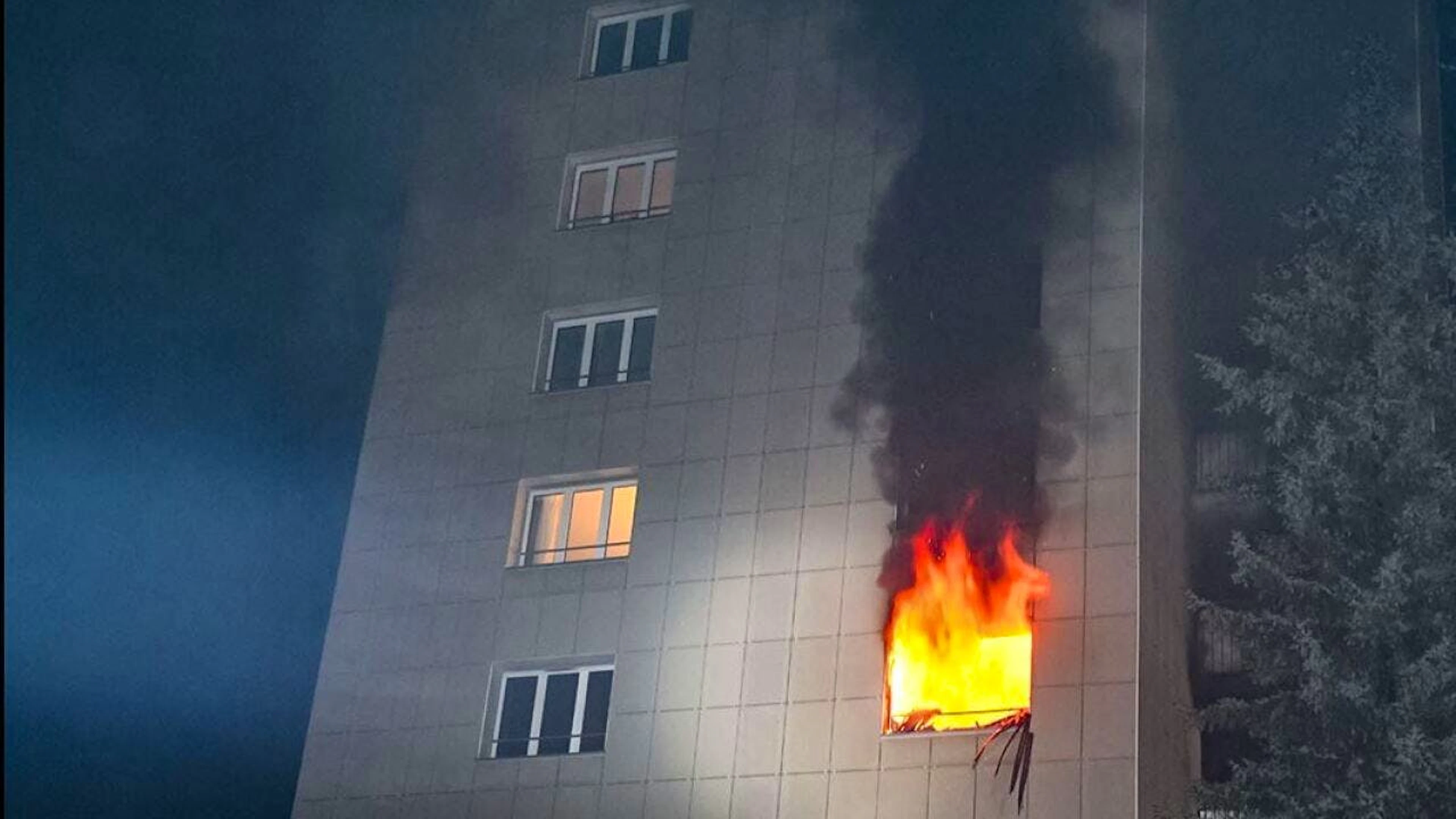 Aus einem Fenster im vierten Stock lodern die Flammen.