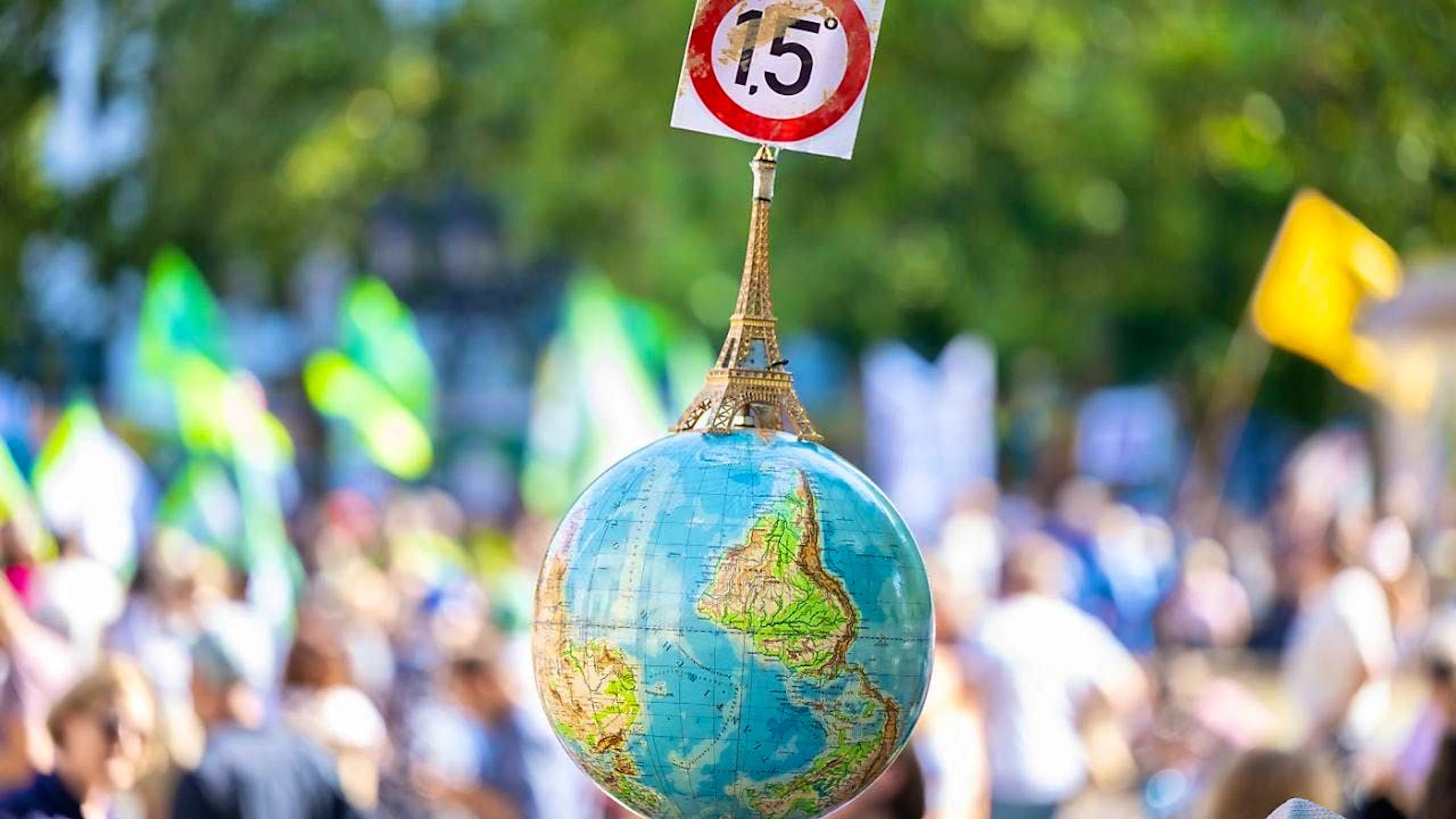 ARCHIVE - A man carries a globe with a miniature Eiffel Tower and the 1.5-degree target of the Paris Climate Agreement at the demonstration in front of the Alte Oper in Frankfurt. Photo: Boris Roessler/dpa