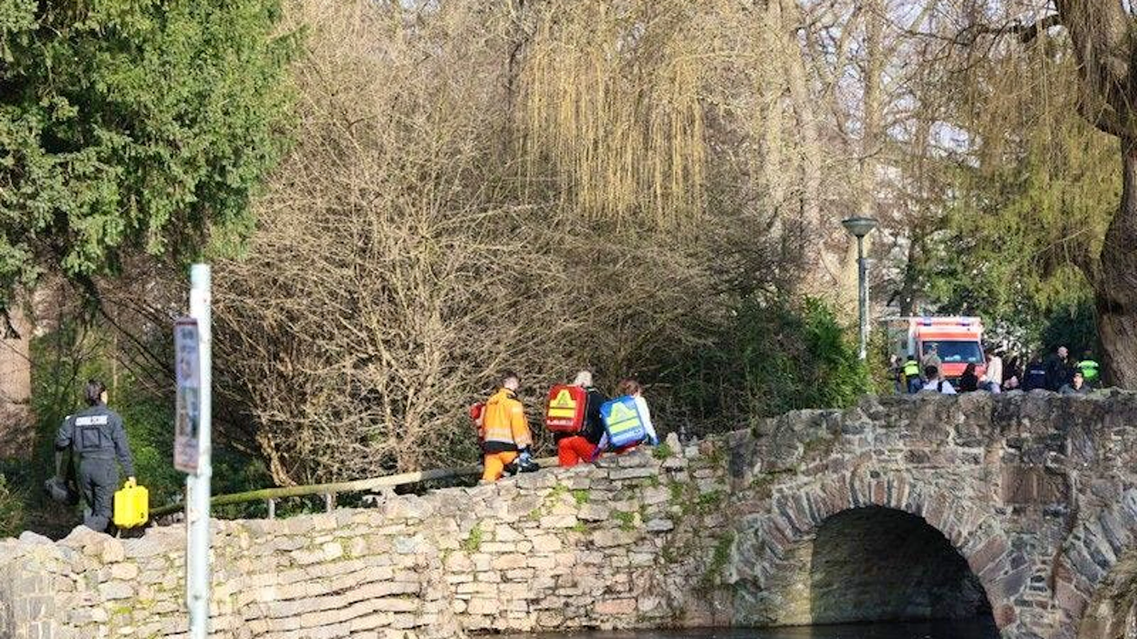  Rettungskräfte und Kriminaltechniker gehen in der Nähe eines Tatortes eine kleine Brücke hinauf.