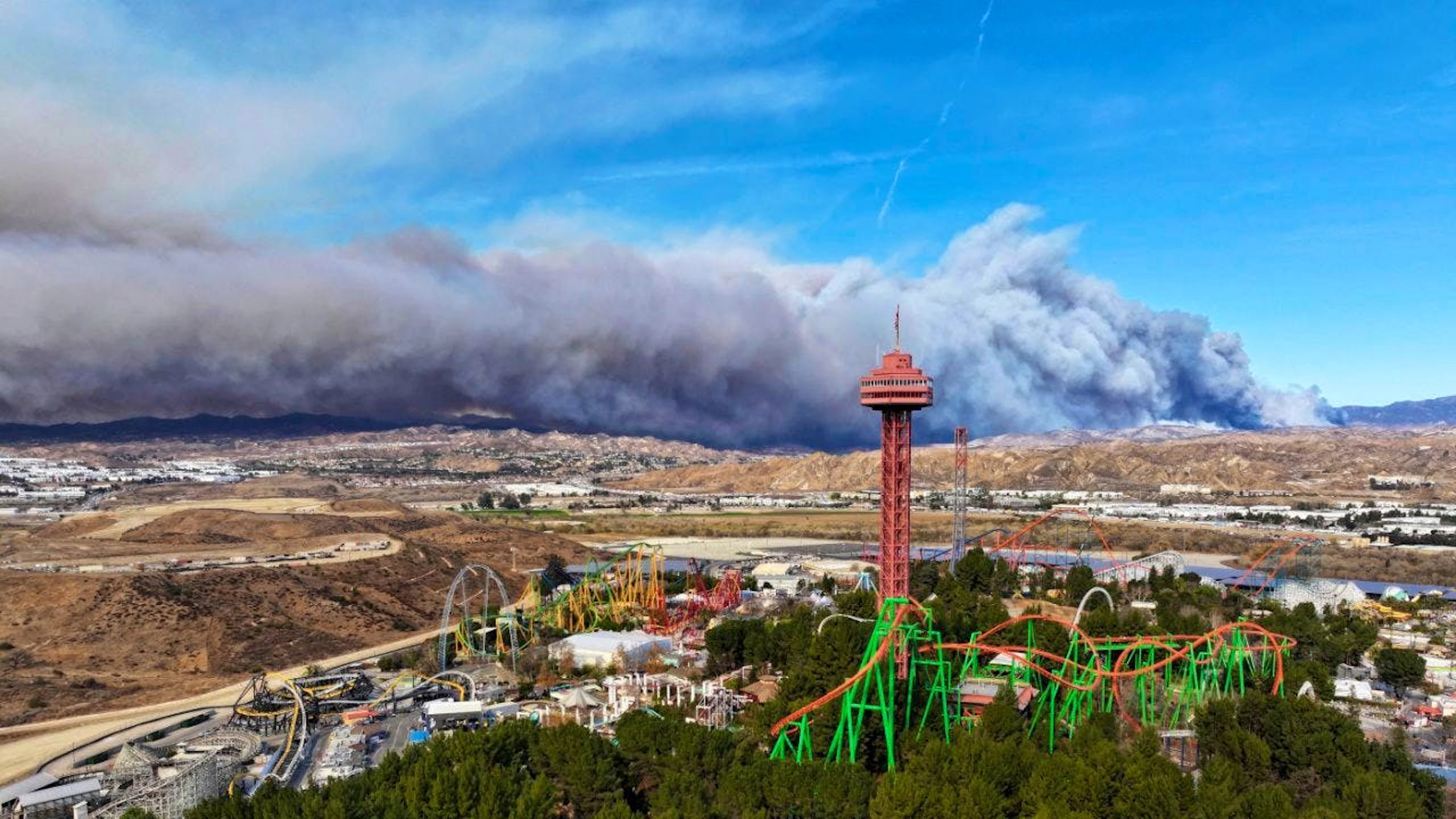 Der Turm von Six Flags Magic Mountain in Santa Clarita mit dem brennenden Hughes-Feuer im Hintergrund. Foto: Dean Musgrove/The Orange County Register/AP/dpa