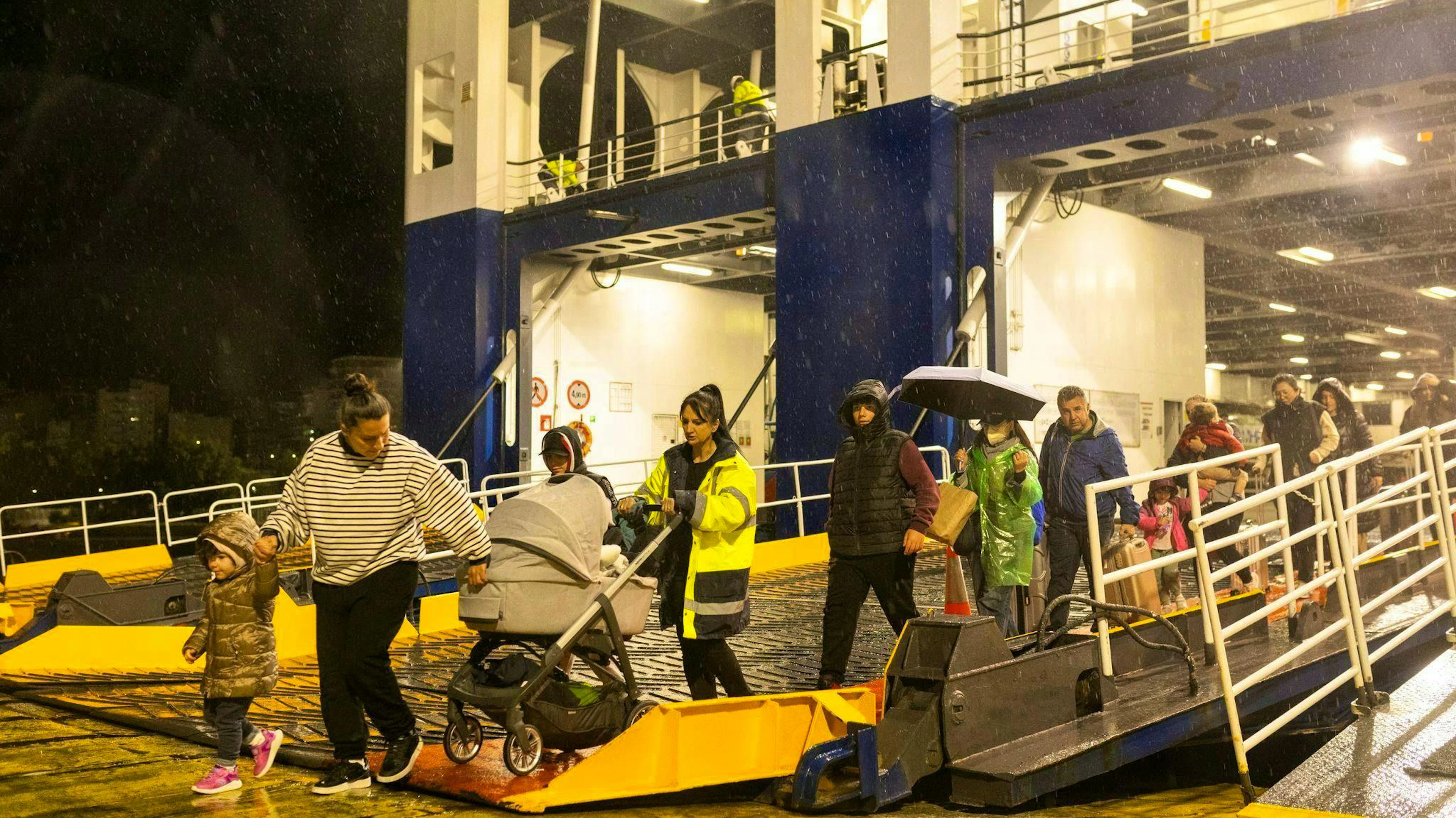 People disembark from a ferry in the port of Piraeus on which they left Santorini.