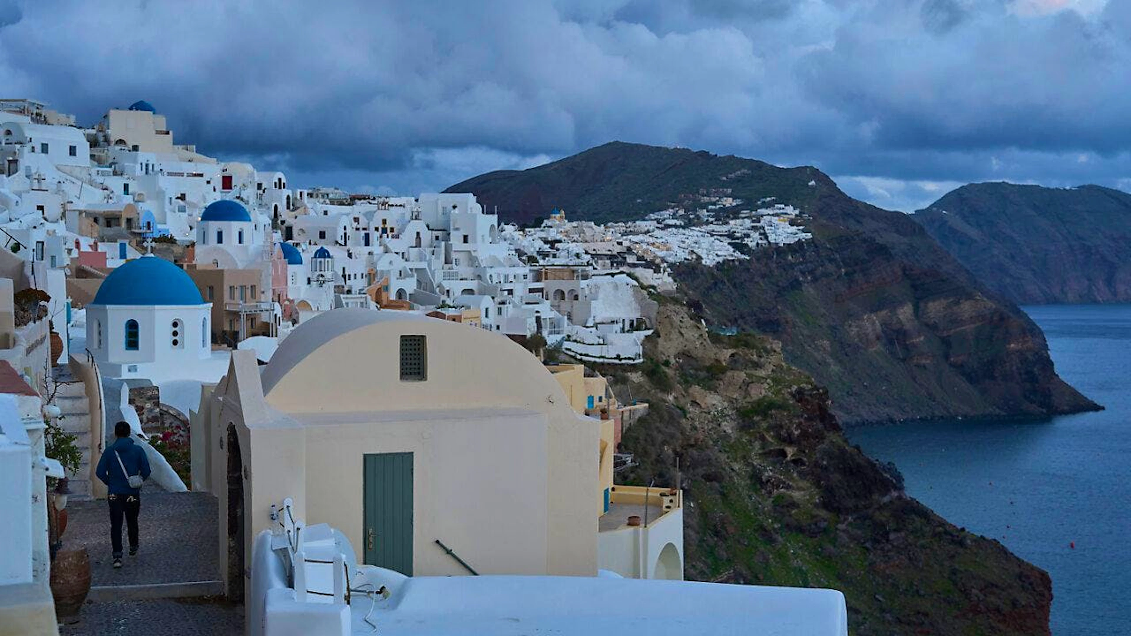 Ein Tourist nähert sich einer orthodoxen Kirche mit blauer Kuppel in Oia auf der erdbebengeschädigten Insel Santorini. Foto: Petros Giannakouris/AP/dpa
