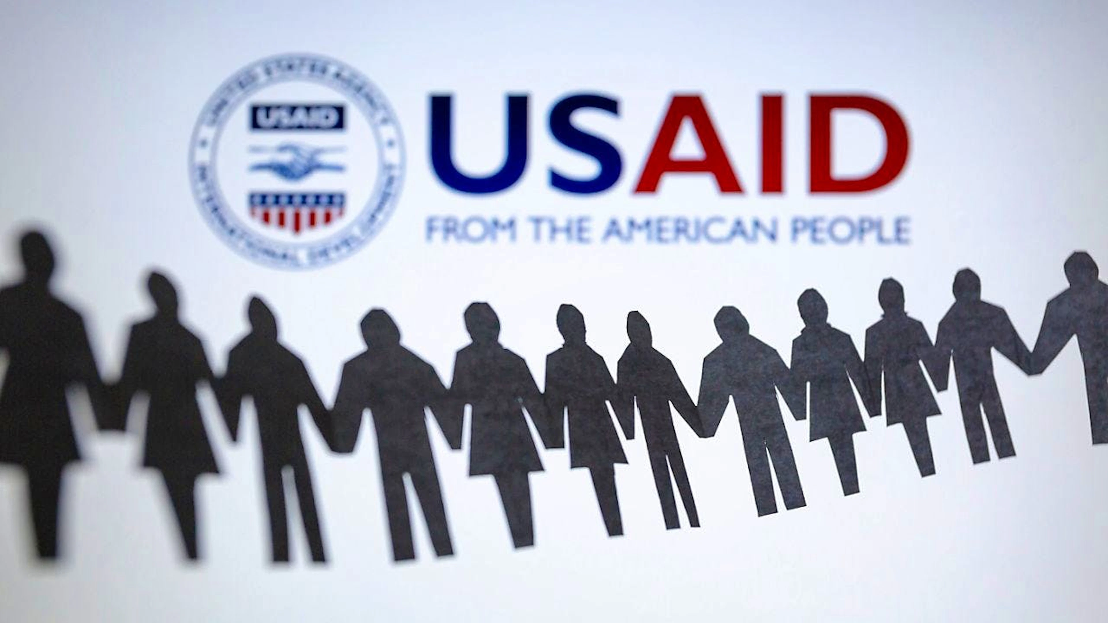 ARCHIV - Das Logo der US-Entwicklungsbehörde, United States Agency for International Development (USAID), ist hinter einer Kette von ausgeschnittenen Papierfiguren zu sehen. Foto: Andre M. Chang/ZUMA Press Wire/dpa