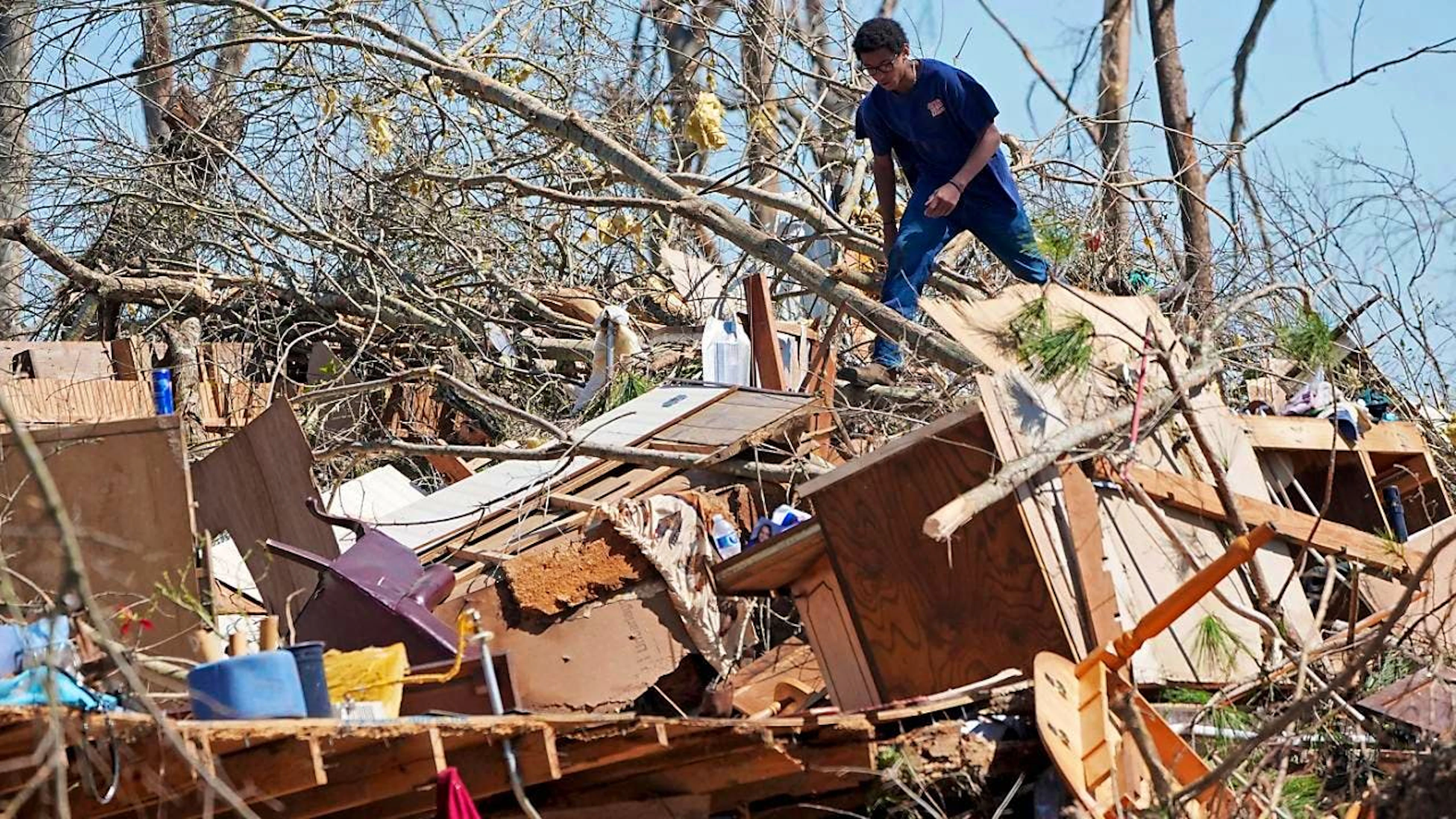 Trey Bridges klettert nach einem Tornado auf einen Berg von Trümmern, um der Familie Blansett bei der Bergung von Gegenständen zu helfen. Foto: Rogelio V. Solis/AP/dpa