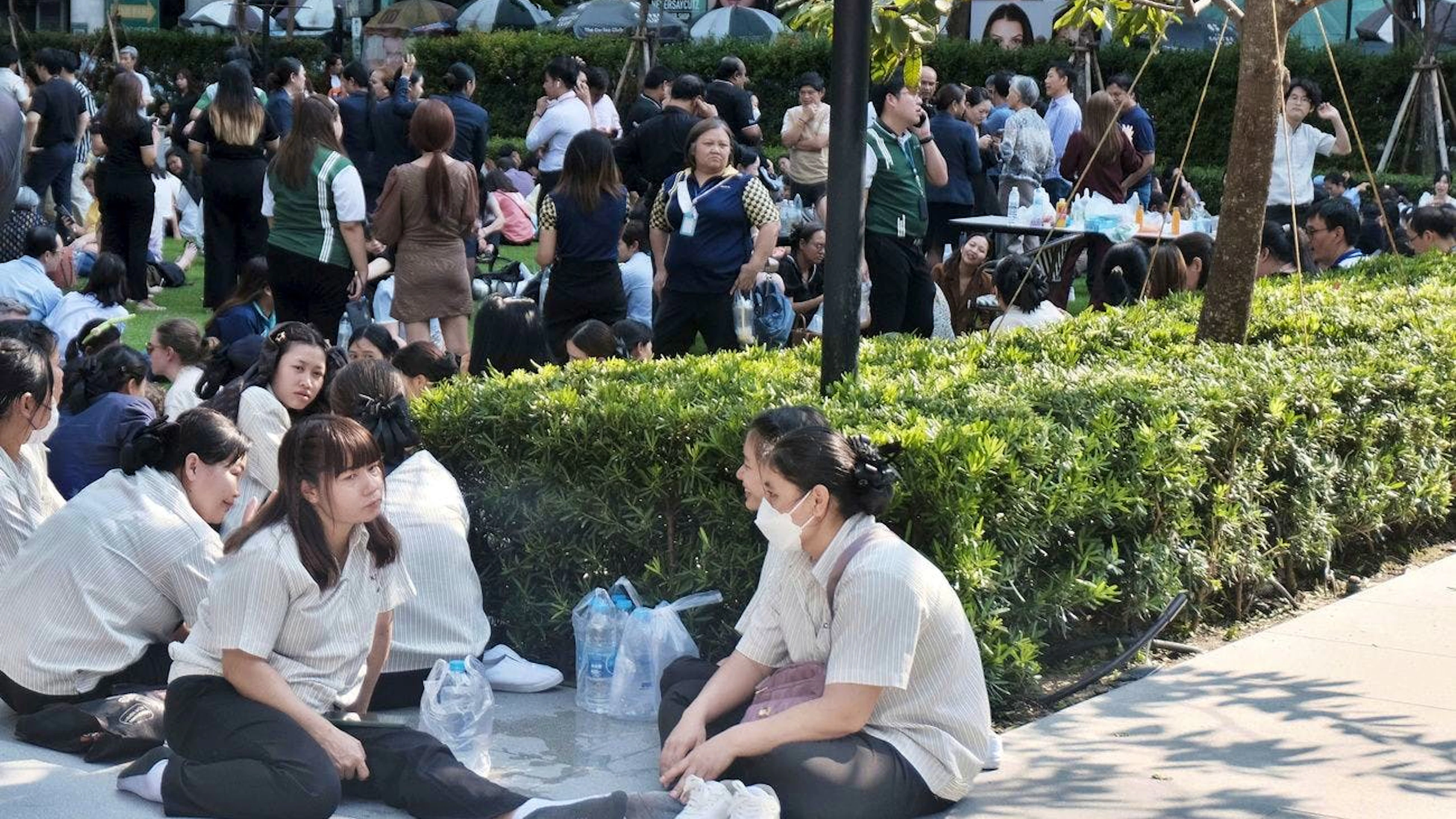 Le persone si rifugiano all'aperto dopo che il terremoto ha scosso i grattacieli nelle vicinanze di Bangkok.
