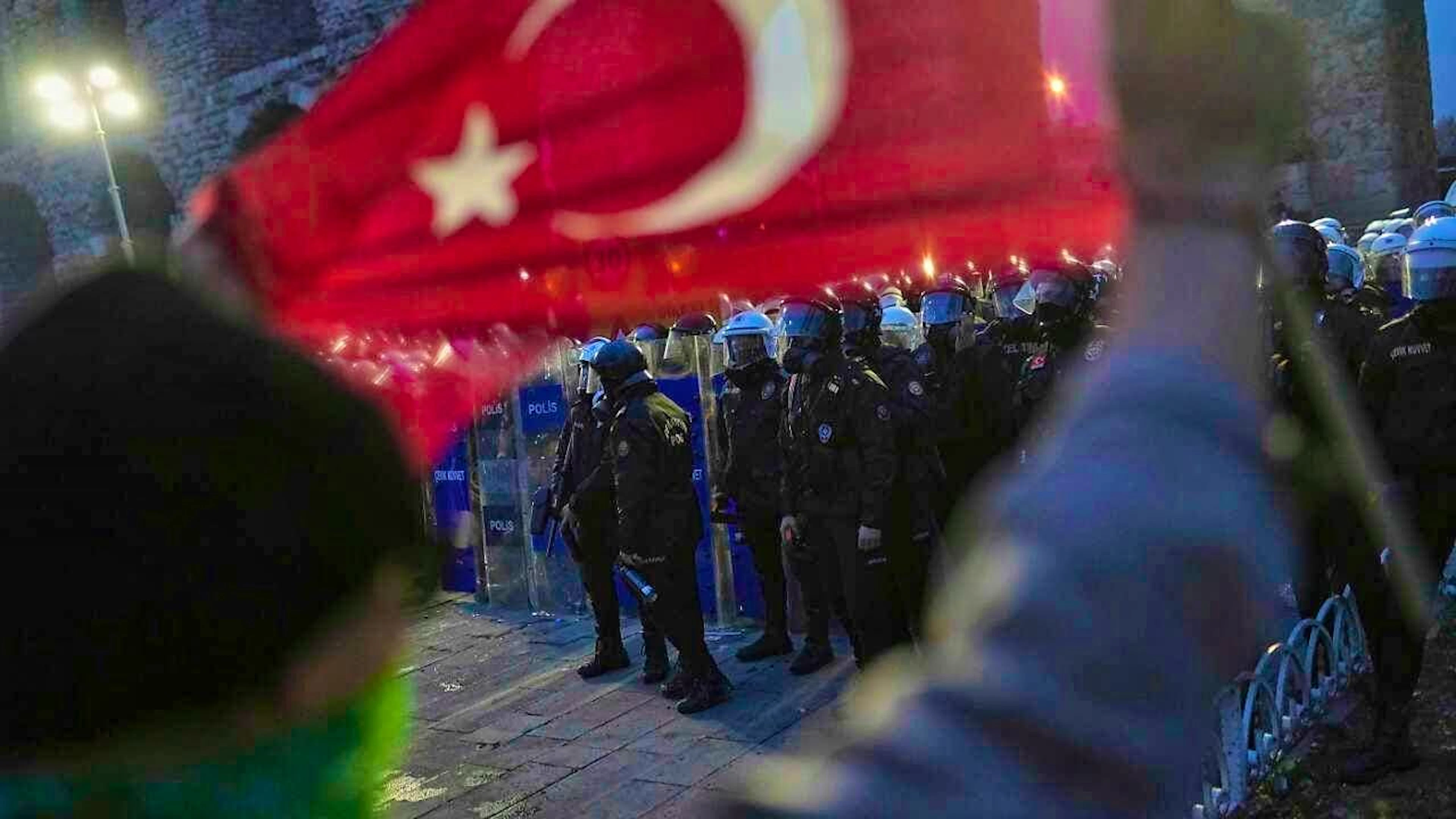 A protester holds a Turkish flag as riot police stand guard during a demonstration following the arrest and detention of Istanbul Mayor Ekrem Imamoglu. Photo: Francisco Seco/AP/dpa