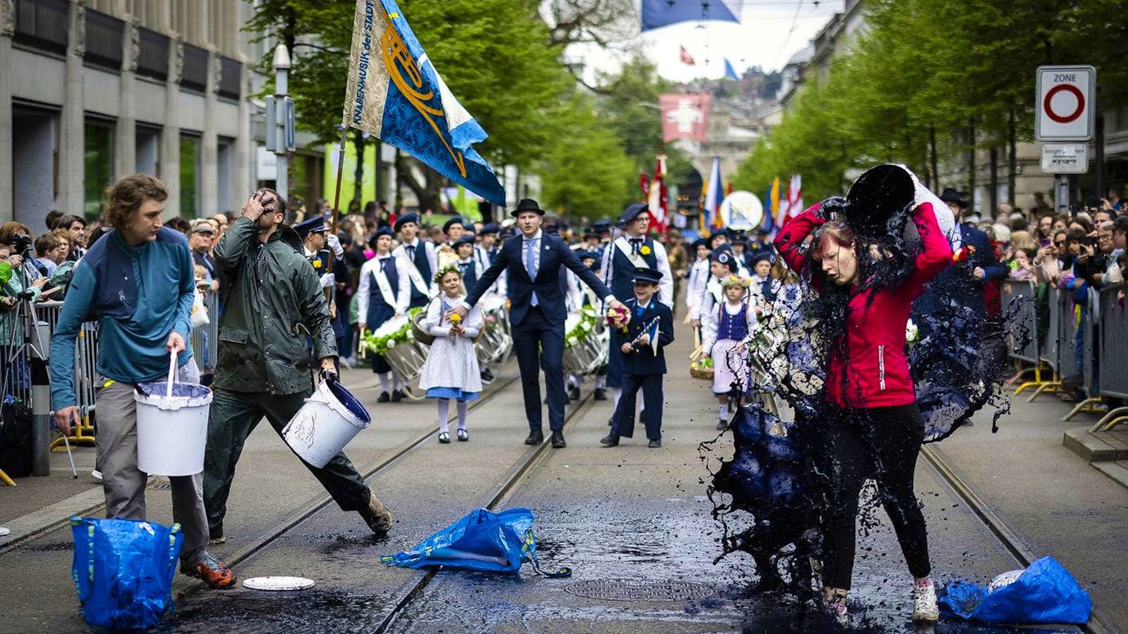 Aktivist*innen von «Drop Fossil Subsidies» übergiessen sich mit einer Flüssigkeit wahrend des traditionellen Umzug der Zünfte.
