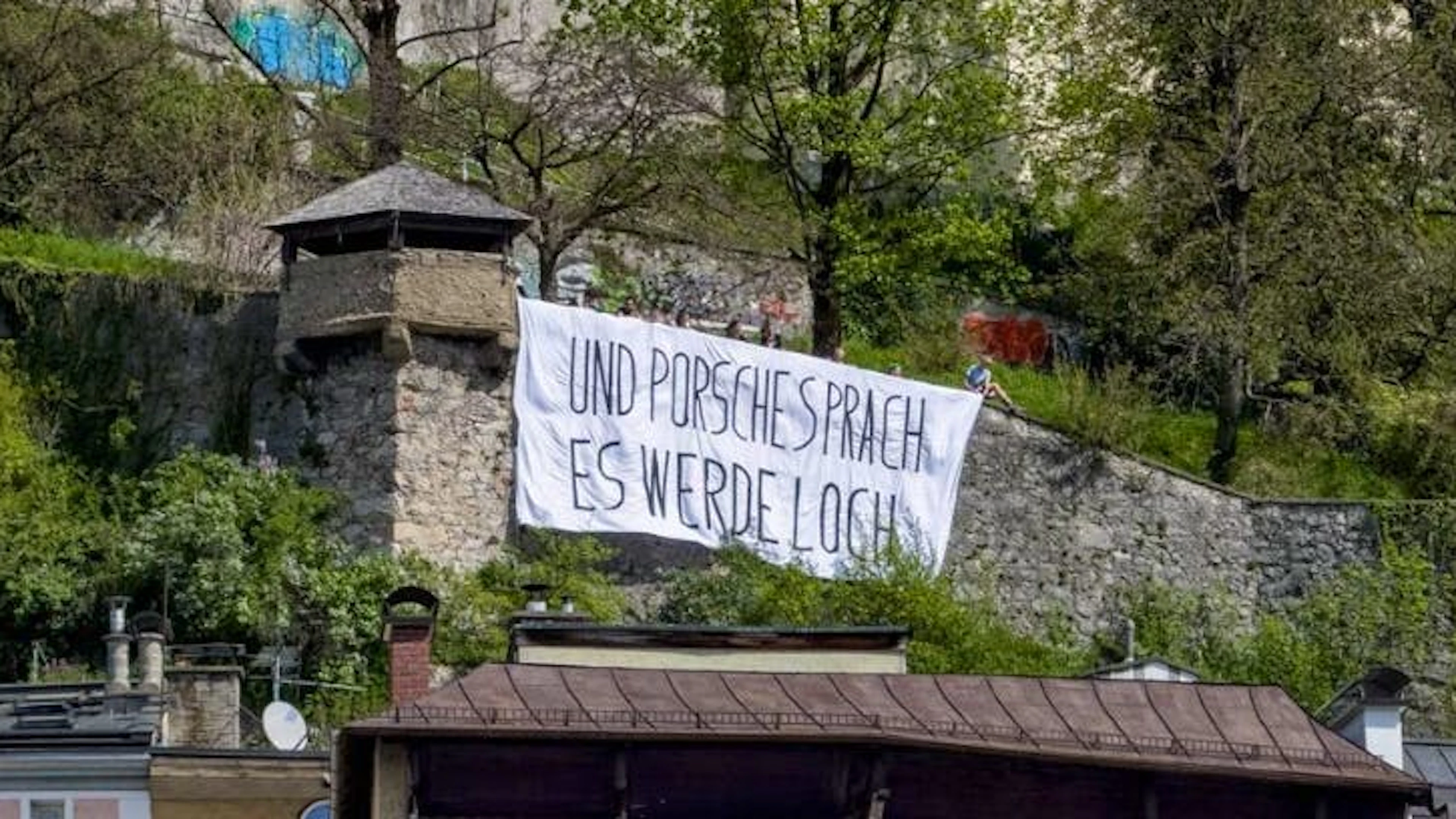 «Und Porsche sprach, es werde Loch» steht auf dem Transparent, das Demonstrant*innen dieser Tage auf dem Salzburger Kapuzinerberg gehisst haben.