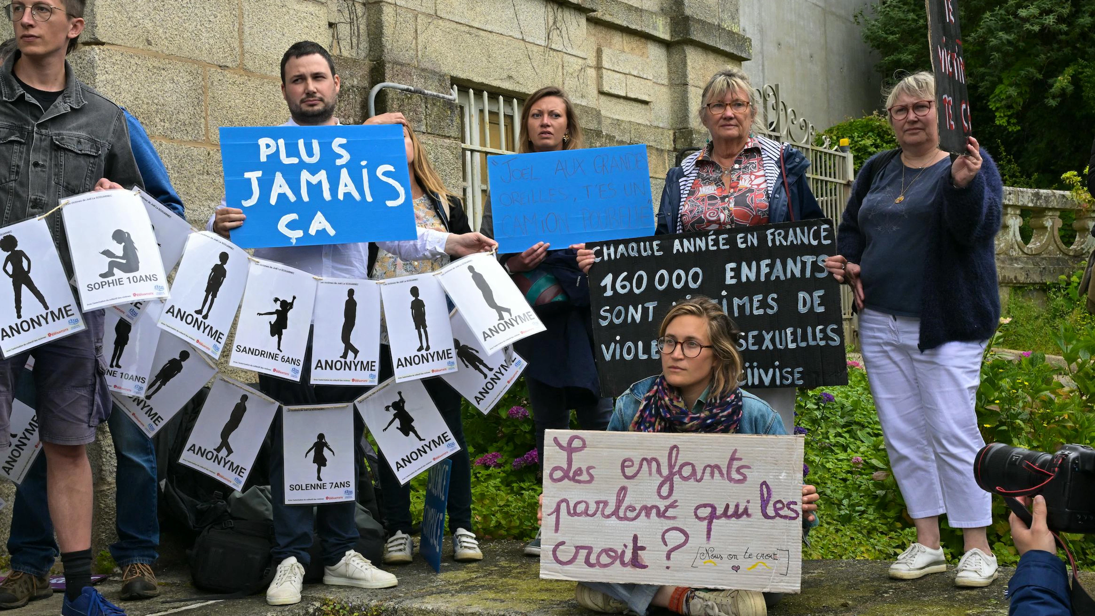 Des manifestants brandissent des pancartes portant les noms des victimes et une autre indiquant « plus jamais ça » (C) lors d'une manifestation de soutien aux victimes au palais de justice en marge du procès du chirurgien à la retraite Joël Le Scouarnec à Vannes, dans le nord-ouest de la France, le 28 mai 2025.