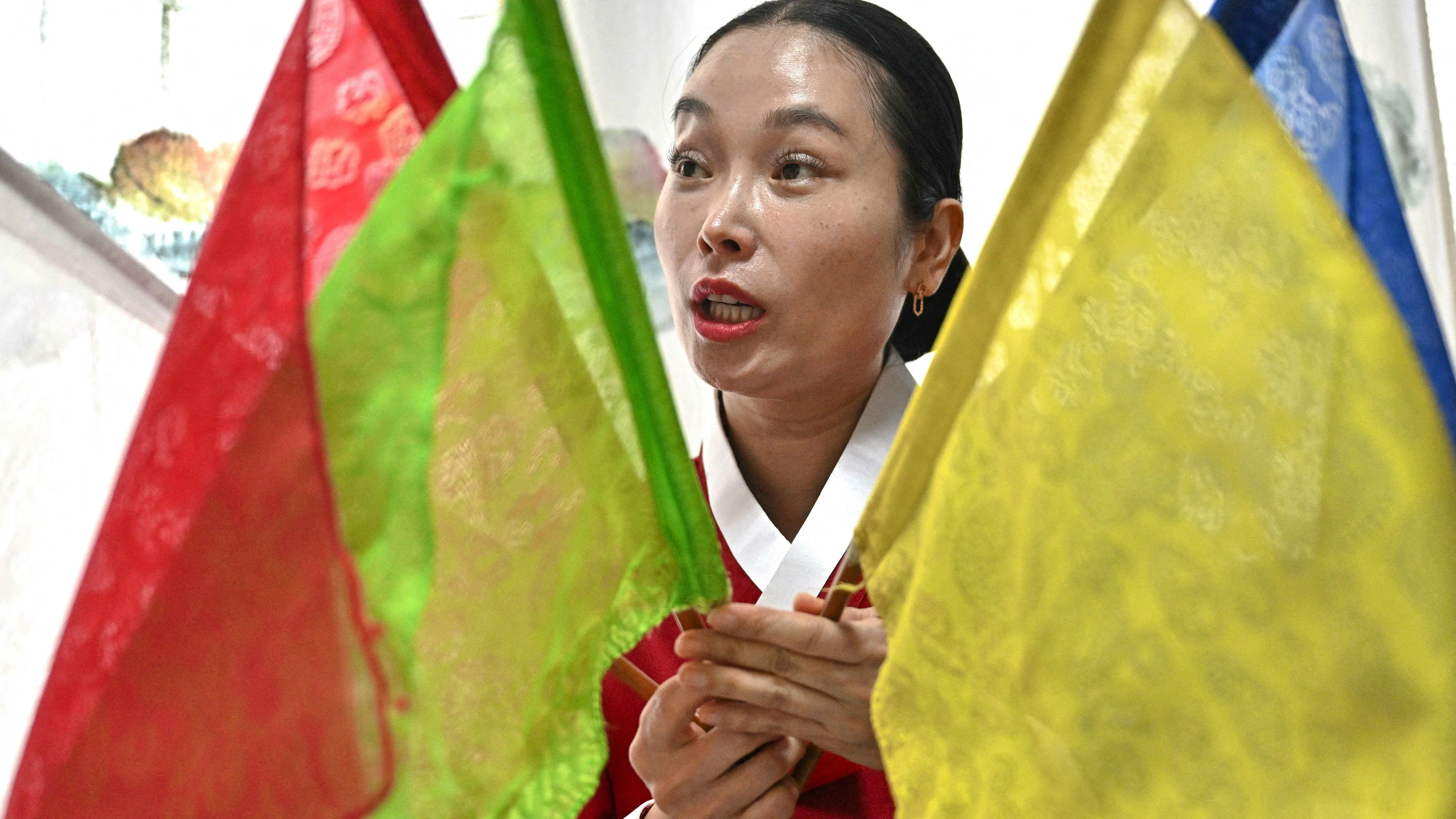 Cette photo prise le 30 mai 2025 montre la chamane Yang Su-bong tenant des drapeaux rituels après une interview avec l'AFP à son domicile à Incheon. Le résultat des élections présidentielles de cette semaine en Corée du Sud est encore inconnu, mais la chamane Yang Su-bong a déclaré à l'AFP que le vainqueur lui était apparu dans une vision il y a plusieurs années. (Photo par Pedro Pardo / AFP) / À LIRE AVEC « SKOREA-VOTE-RELIGION-SHAMANS, FOCUS » PAR SHIM KYU-SEOK