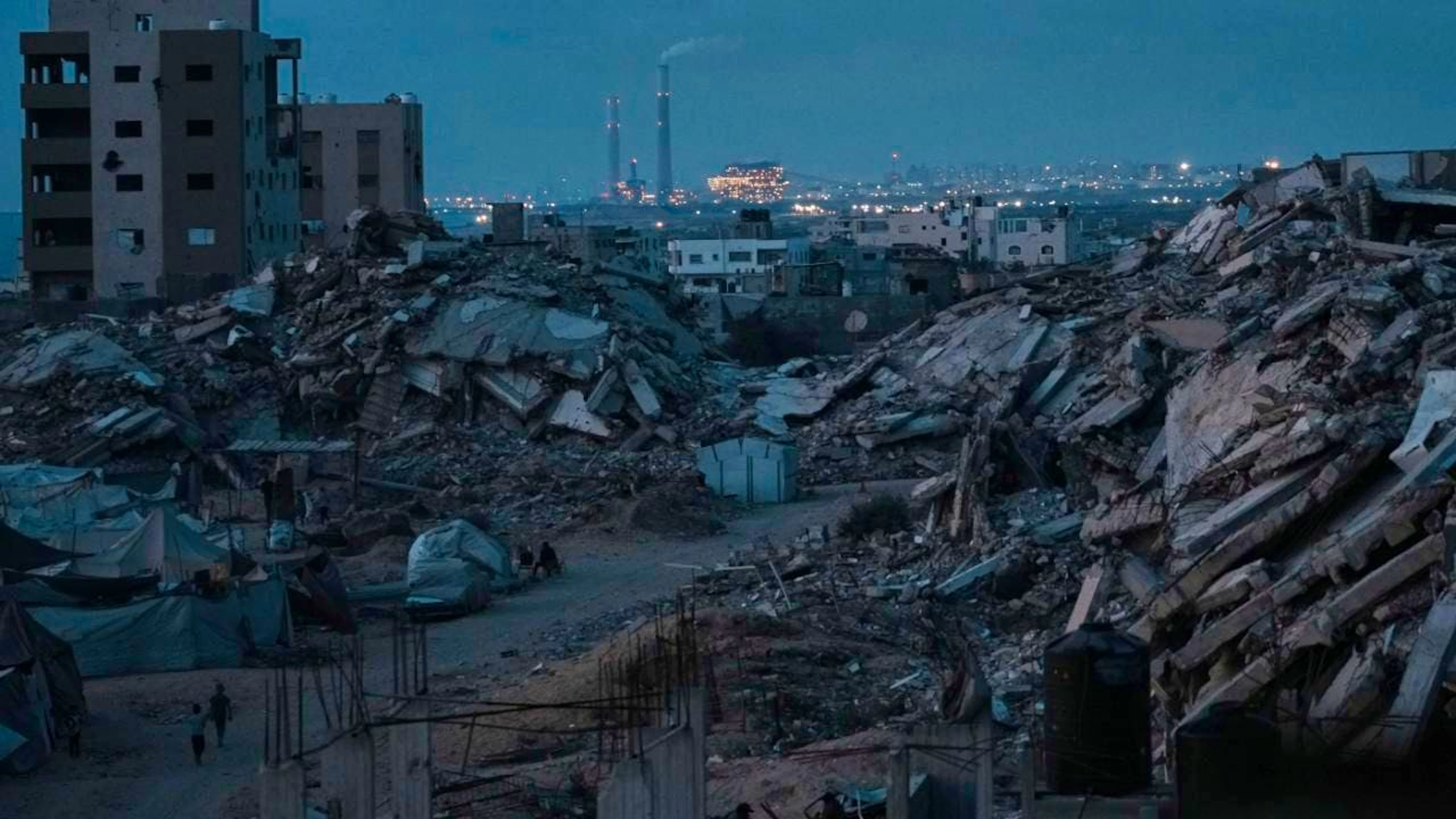 Palästinenser, die durch die israelische Luft- und Bodenoffensive auf den Gazastreifen vertrieben wurden, halten sich in der Abenddämmerung in einem Gebiet bei Gaza-Stadt umgeben von zerstörten Gebäuden auf. Foto: Jehad Alshrafi/AP/dpa