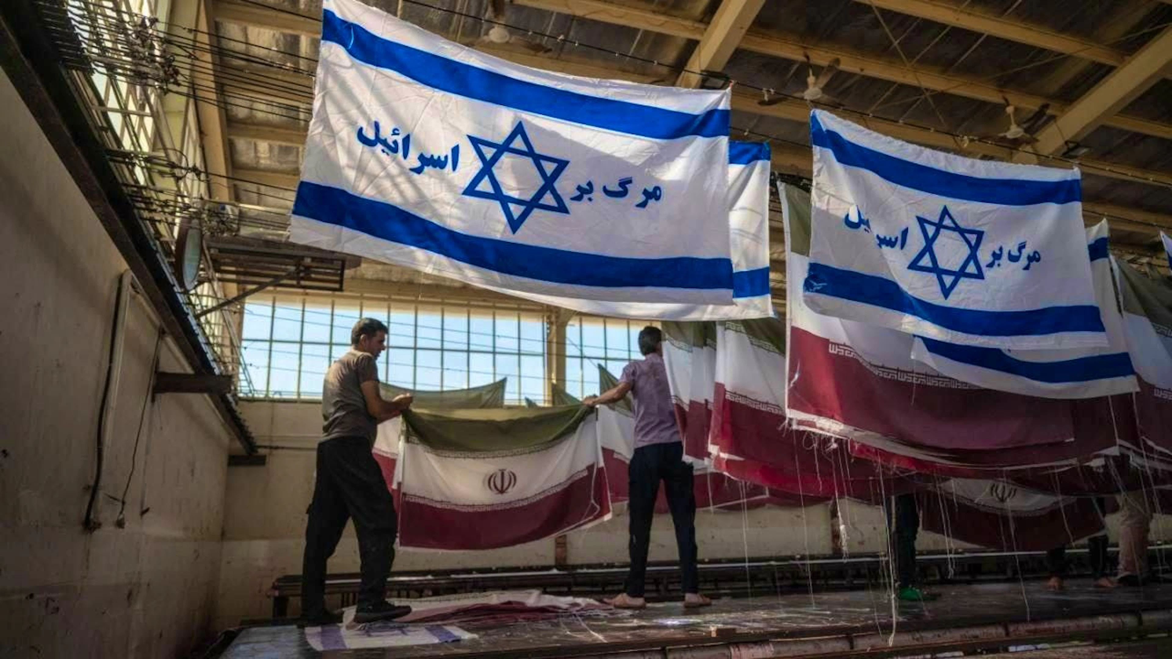 ARCHIVE - Employees at a factory hang flags after drying. Photo: Arne Immanuel Bänsch/dpa