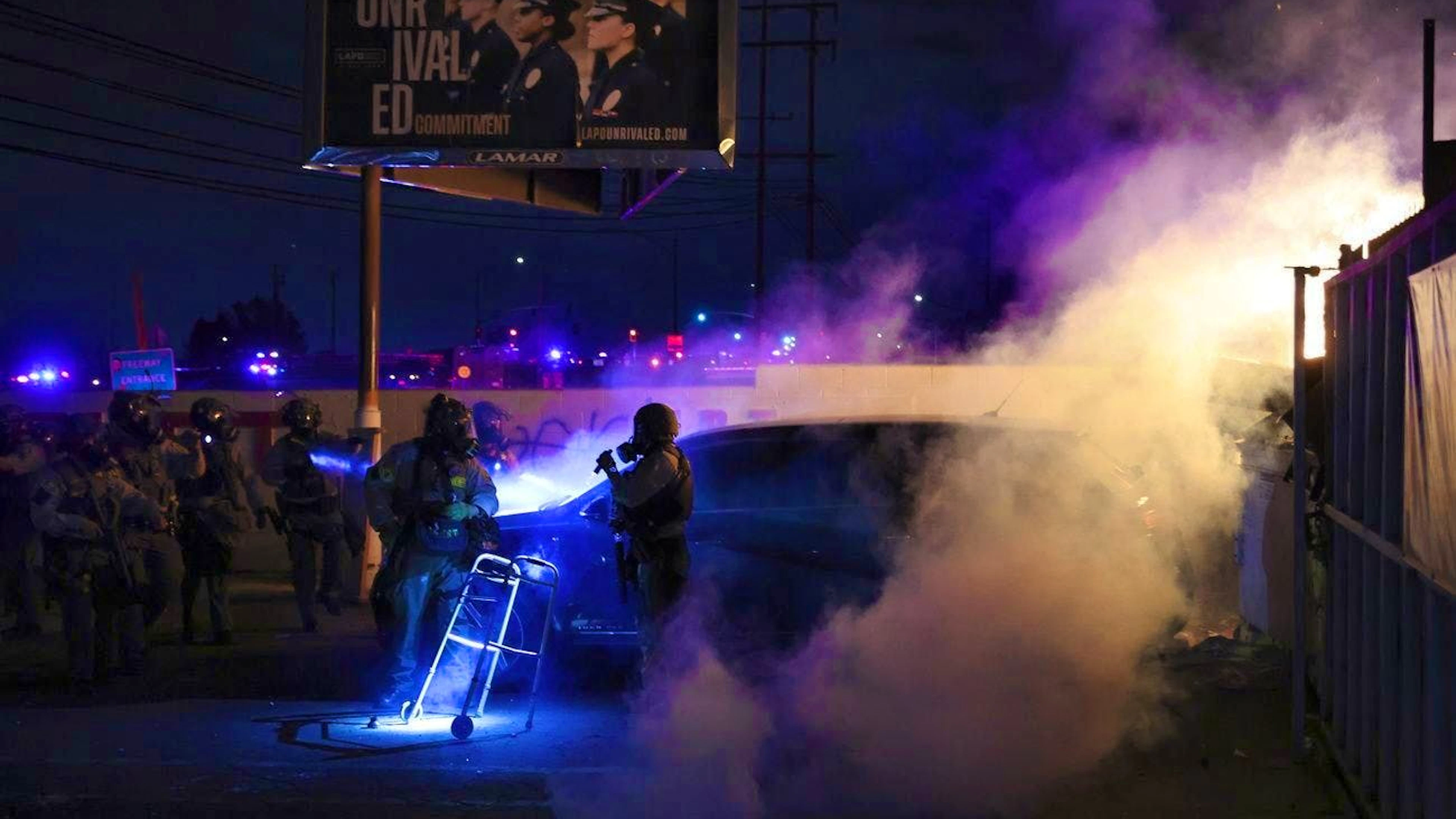 Law enforcement investigate a car with a person inside during a protest in Compton, Calif., Saturday, June 7, 2025, after federal immigration authorities conducted operations. (AP Photo/Ethan Swope)