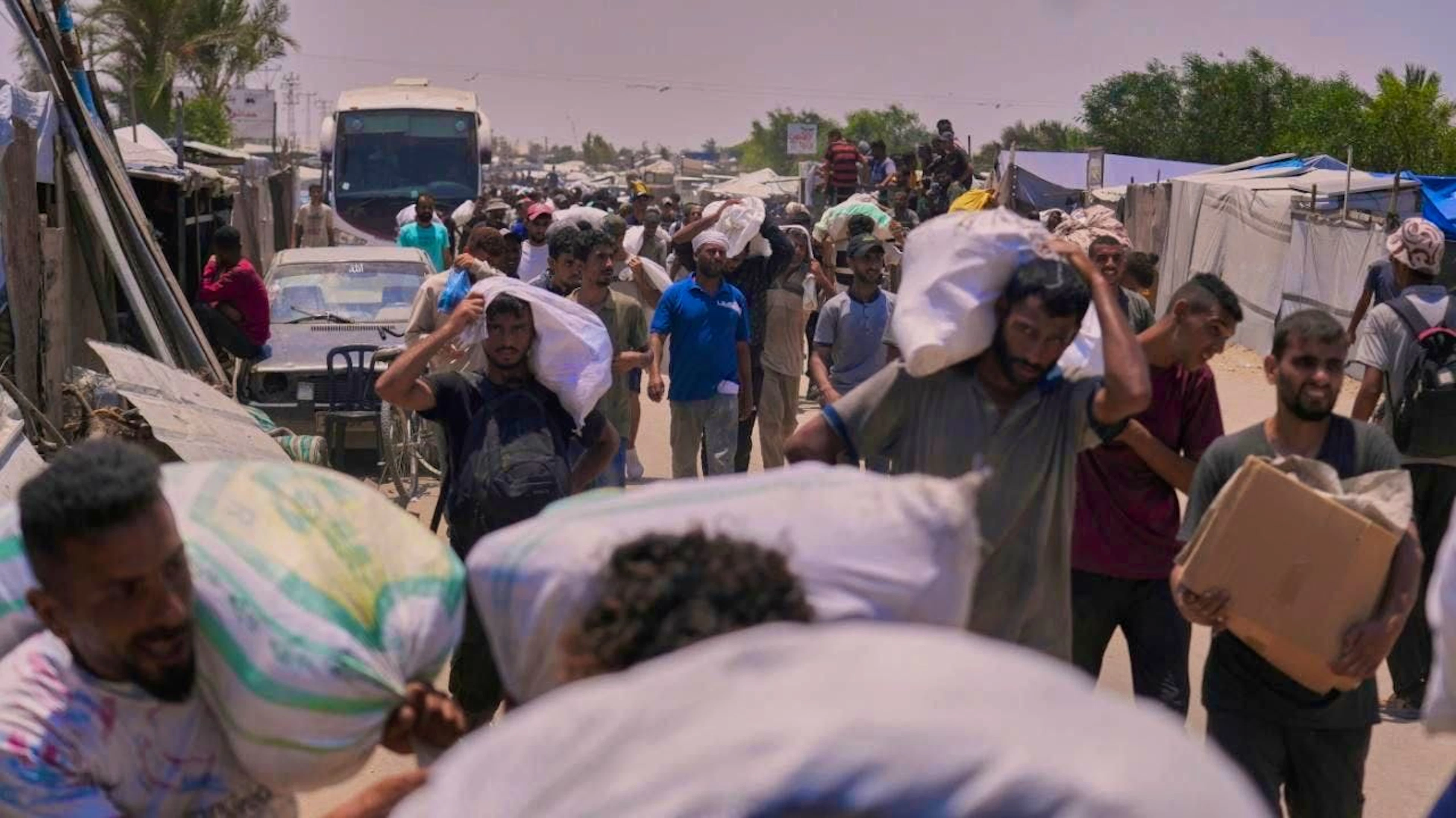 dpatopbilder - Palestinians carry bags of food and humanitarian aid packages delivered by the Gaza Humanitarian Foundation. Photo: Abdel Kareem Hana/AP/dpa