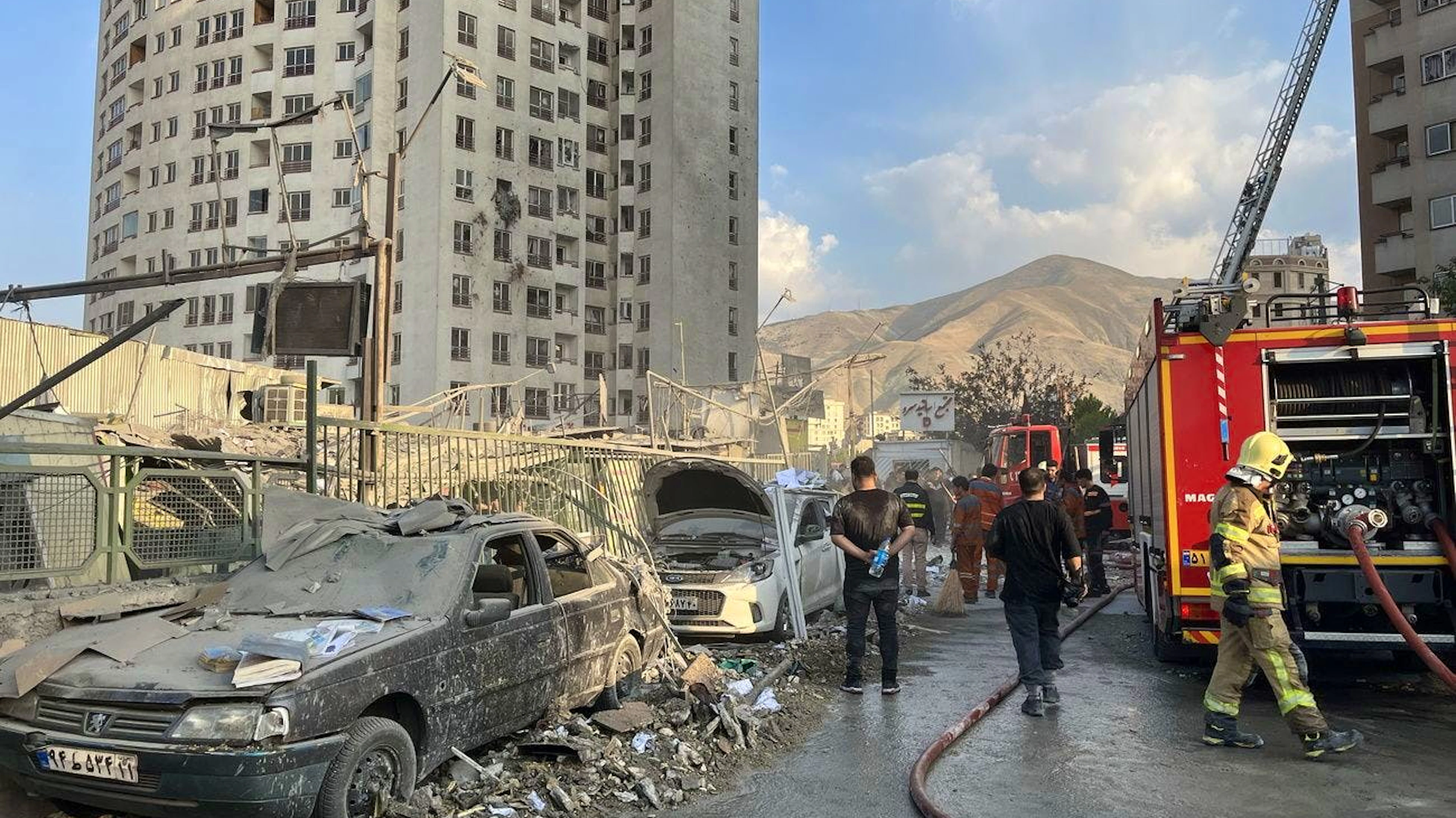 Des pompiers interviennent à l'extérieur d'un bâtiment touché par des frappes aériennes israéliennes au nord de Téhéran, en Iran, le 13 juin 2025.