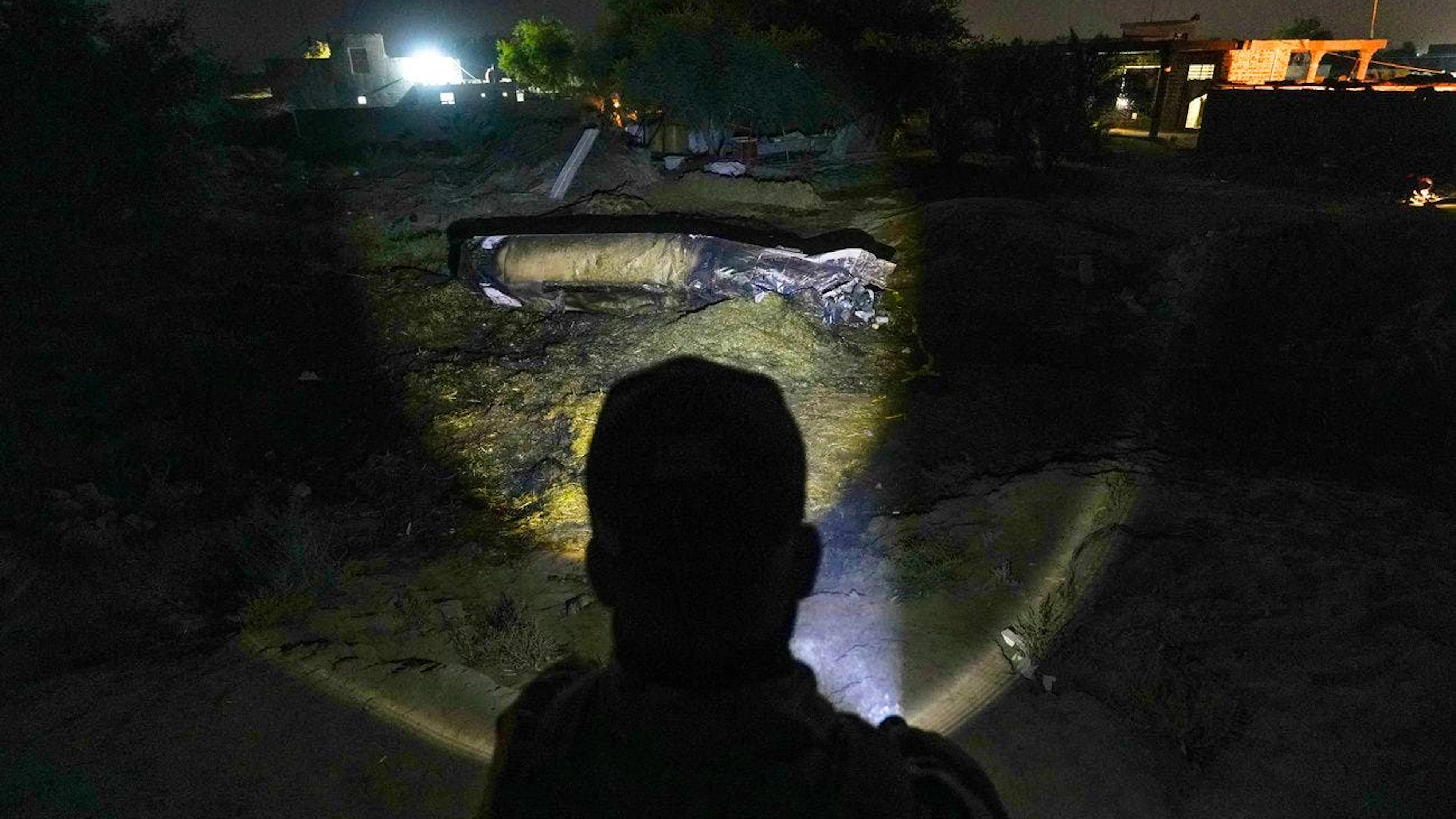 Un homme éclaire les restes d'un missile tombé dans un champ entre Najaf et Karbala, en Irak, le vendredi 13 juin 2025.