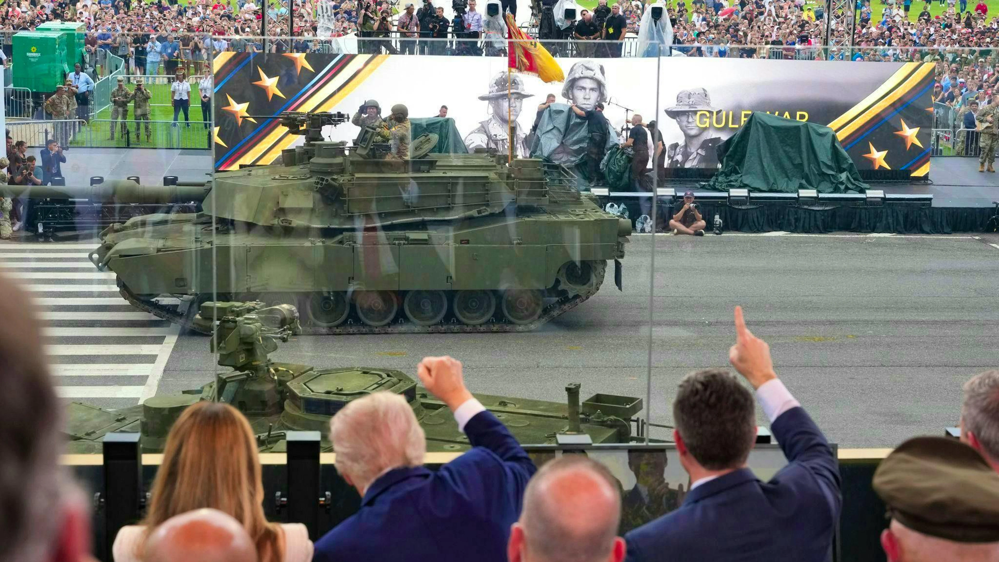 Military vehicles roll past the president during the parade. 
