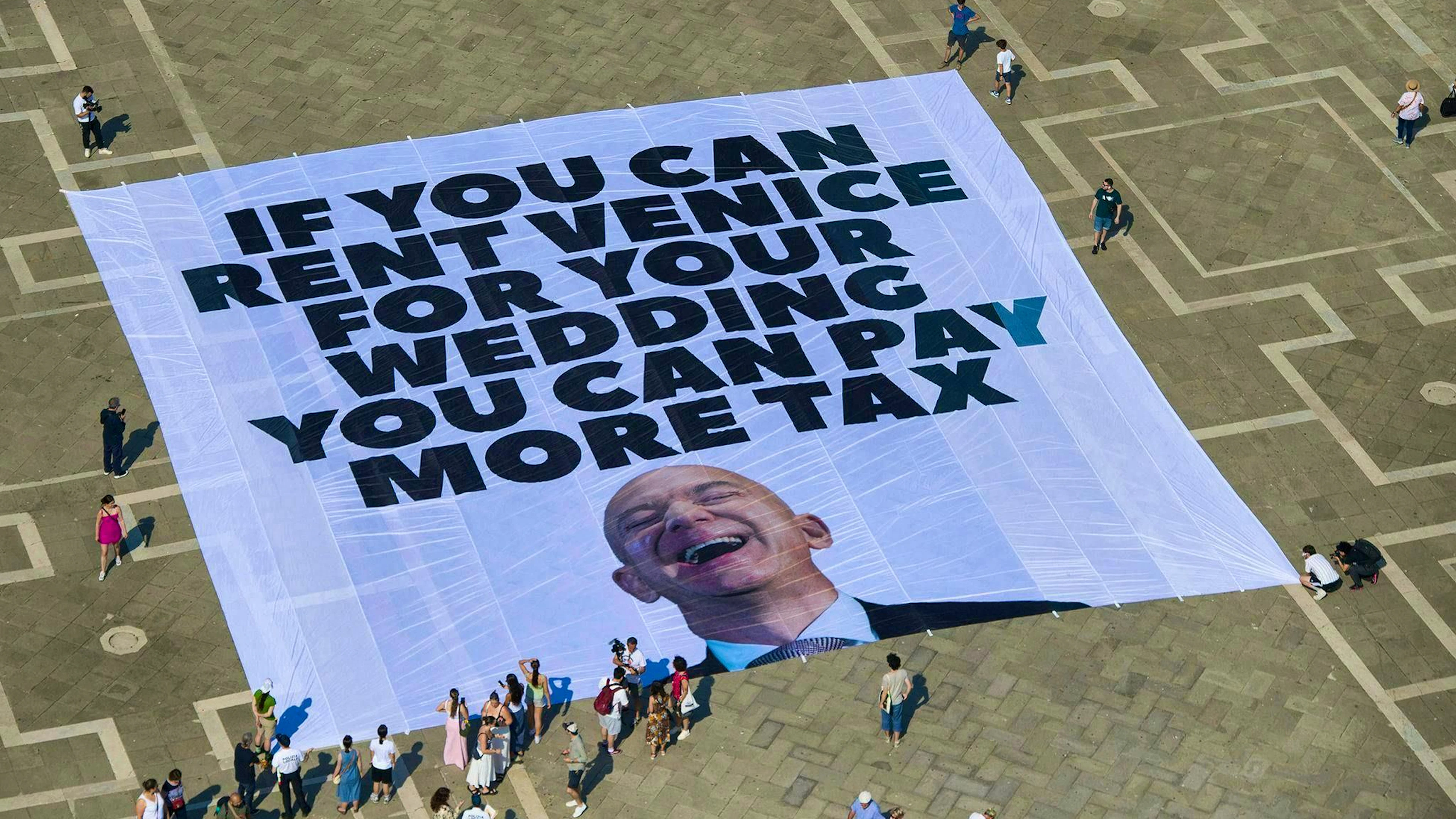 Avec une affiche sur la place Saint-Marc, des activistes de Greenpeace demandent que Bezos soit davantage taxé.
