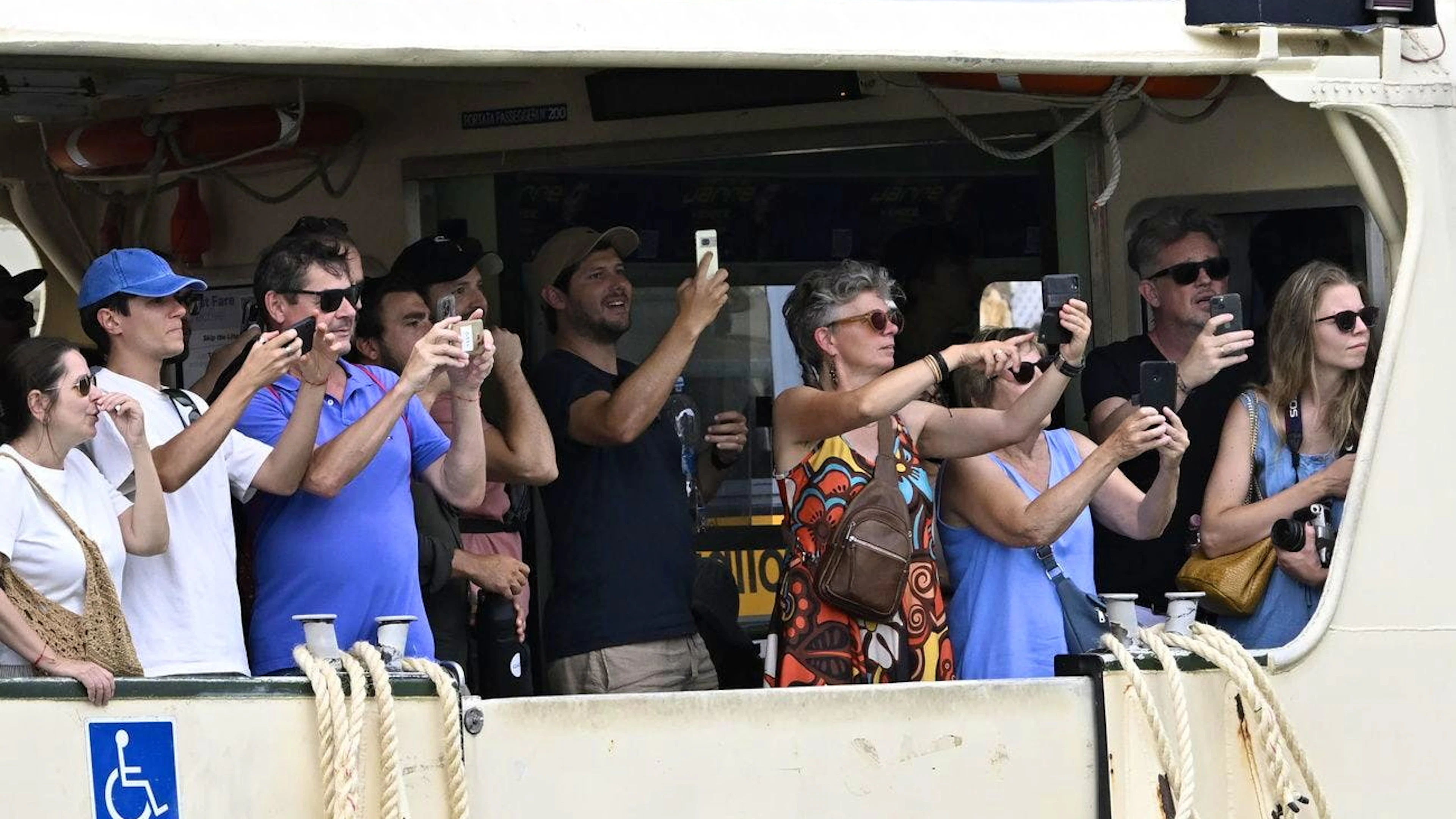 Die Hochzeit ist für Tourist*innen ein Spektakel: Passagiere einer Fähre beobachten die Hochzeitsgäste.